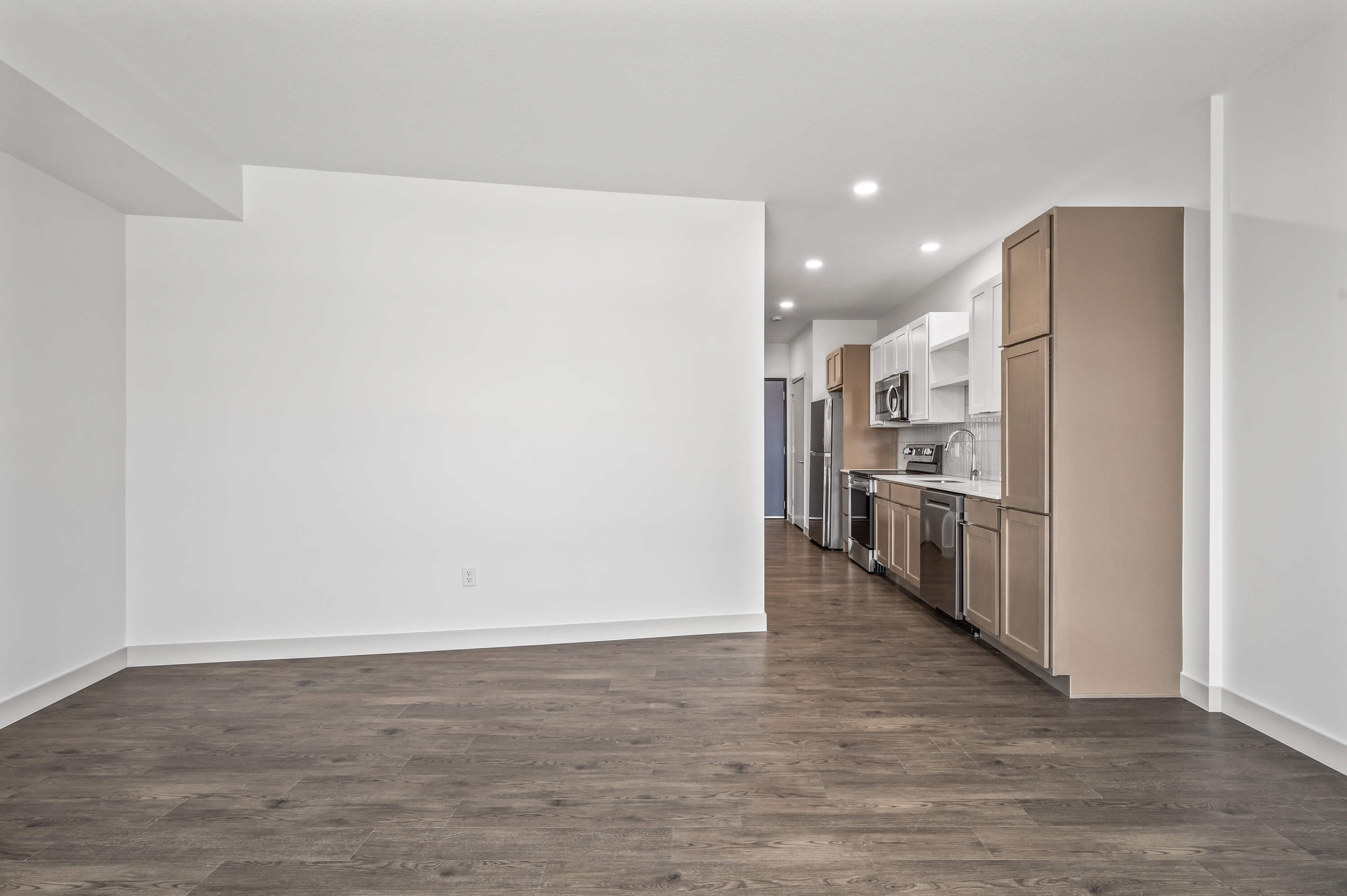 Laundry area with a stacked washer and dryer unit located off the kitchen with a view of the living room area.