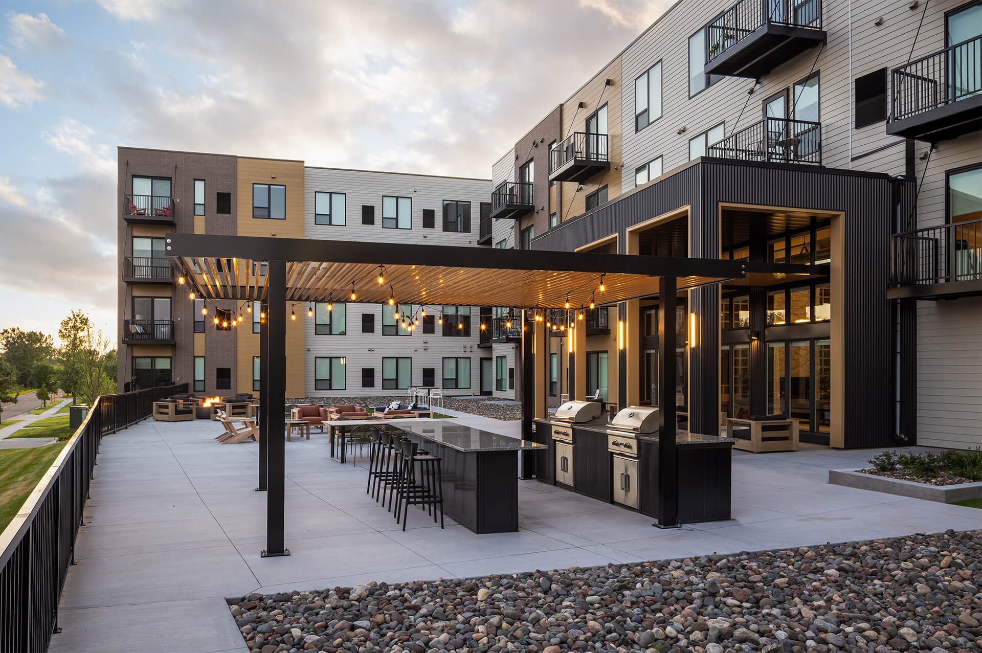Outdoor grilling area with pergola and string lights at The Harlan Oakdale