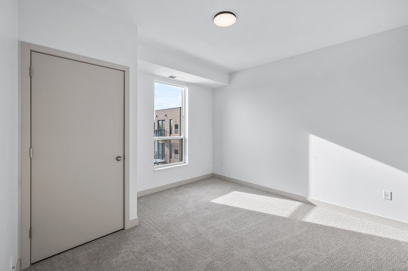 Carpeted bedroom with window and closed door