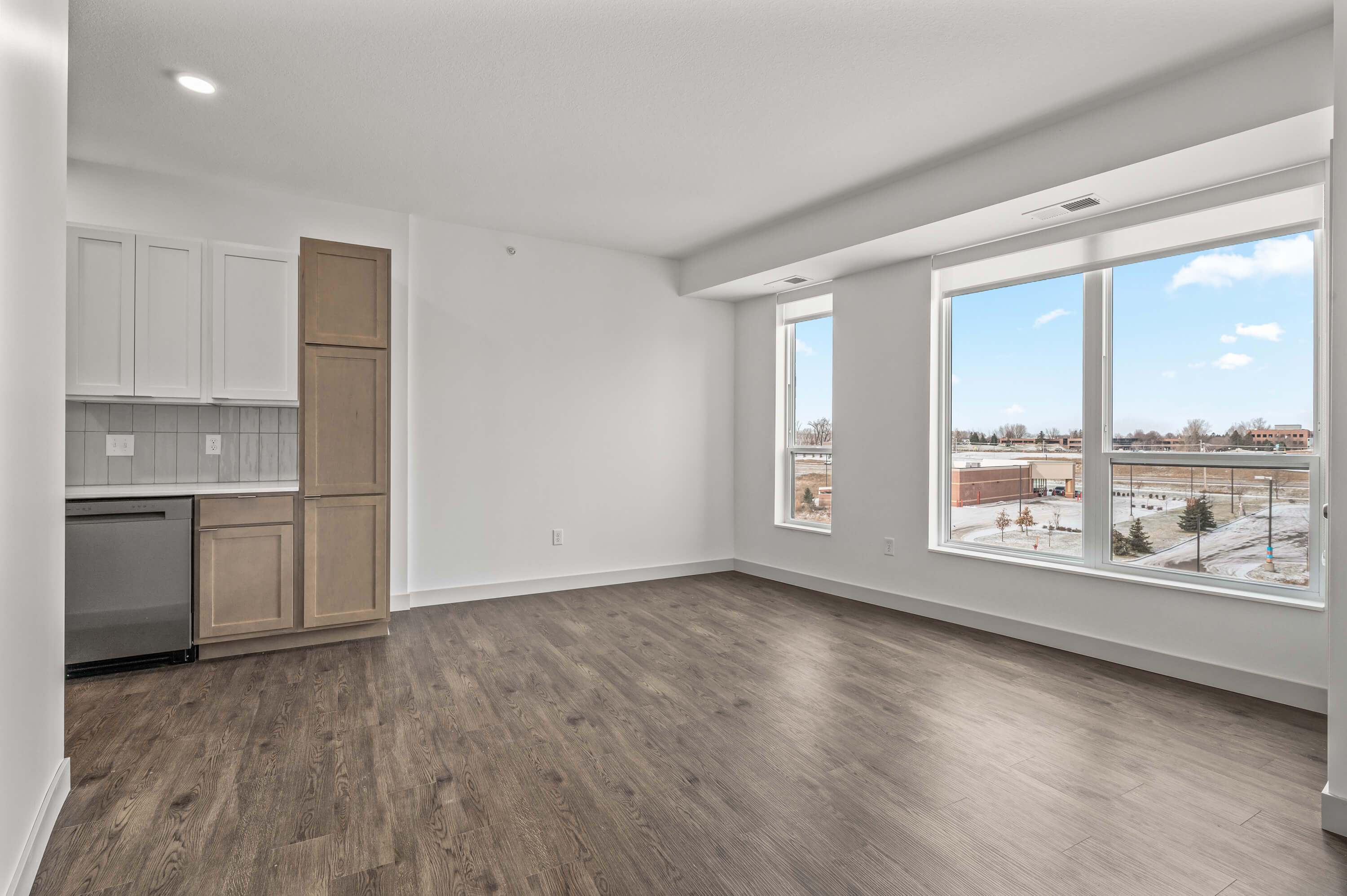 A living room with large windows providing ample natural light and wood flooring