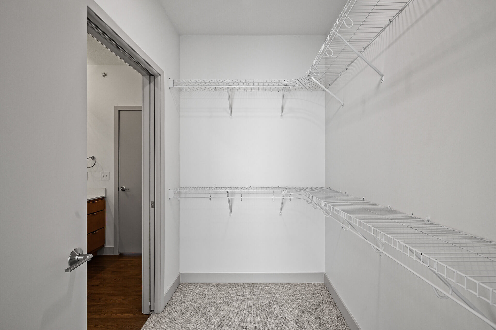 Spacious closet with storage shelves and doorway view to bathroom.