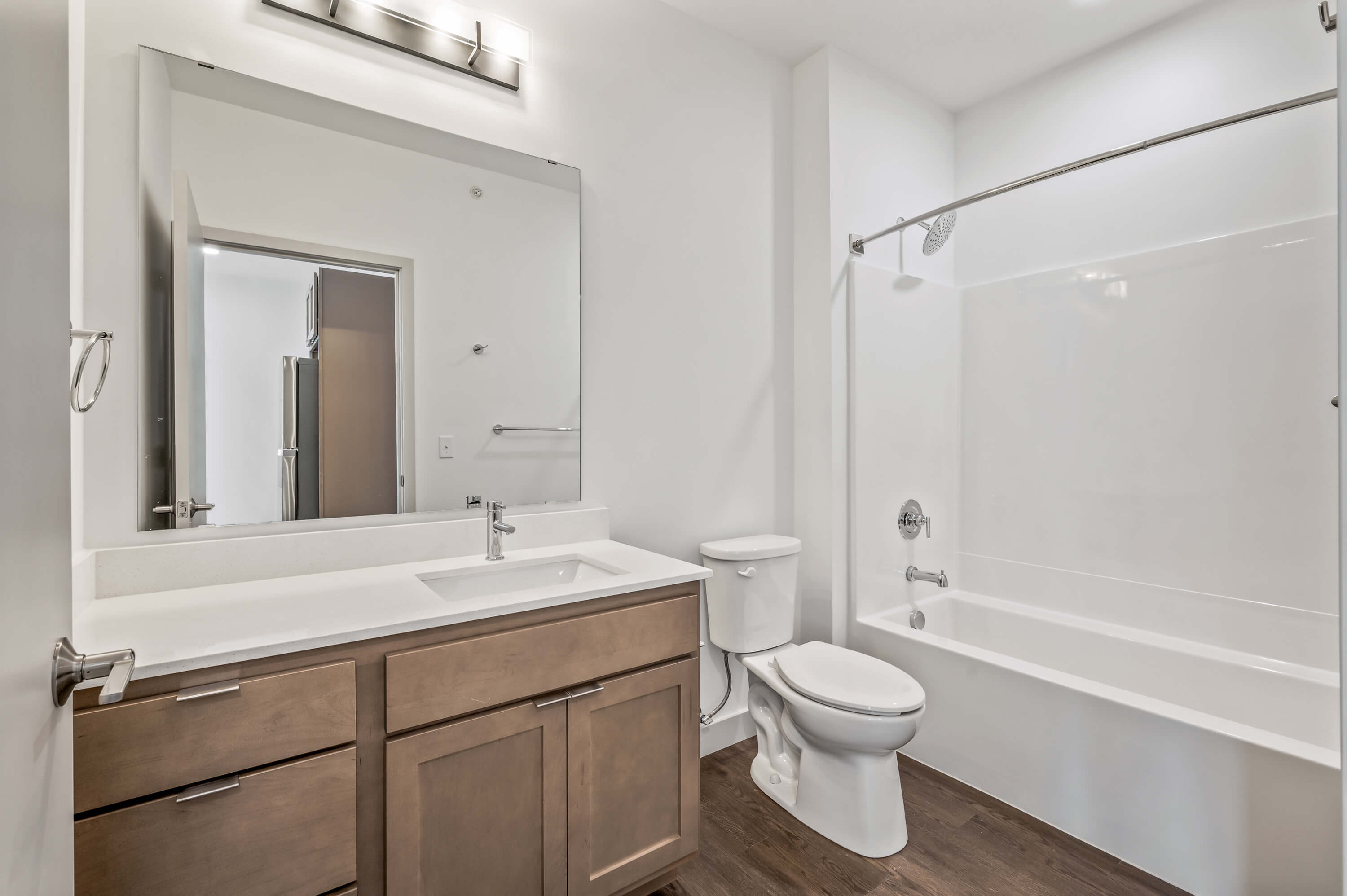 Bathroom with a large mirror, sink, toilet, and bathtub with a showerhead.