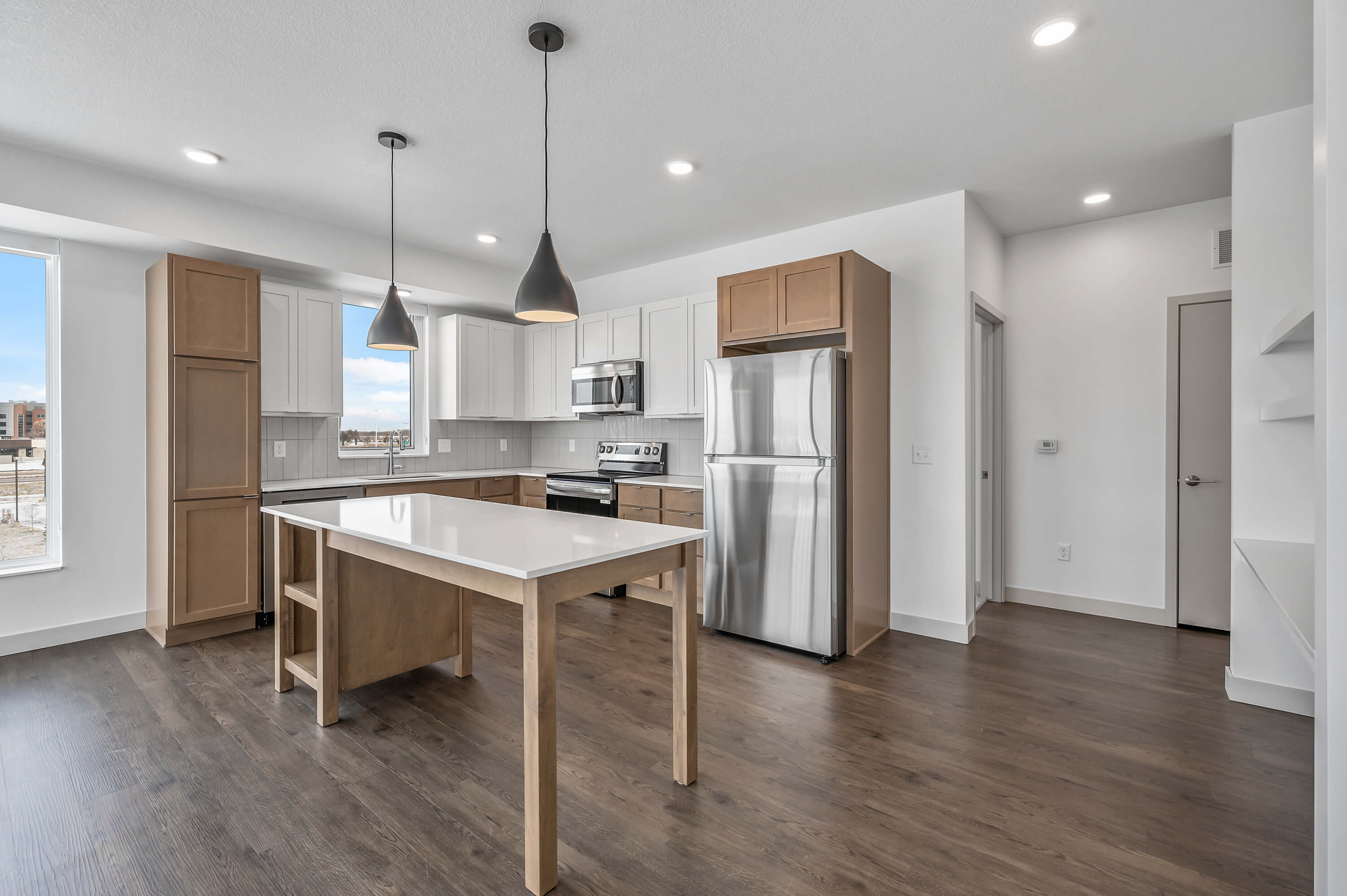 A wider view of the kitchen, showing additional shelving on the wall and pendant lighting above the island.