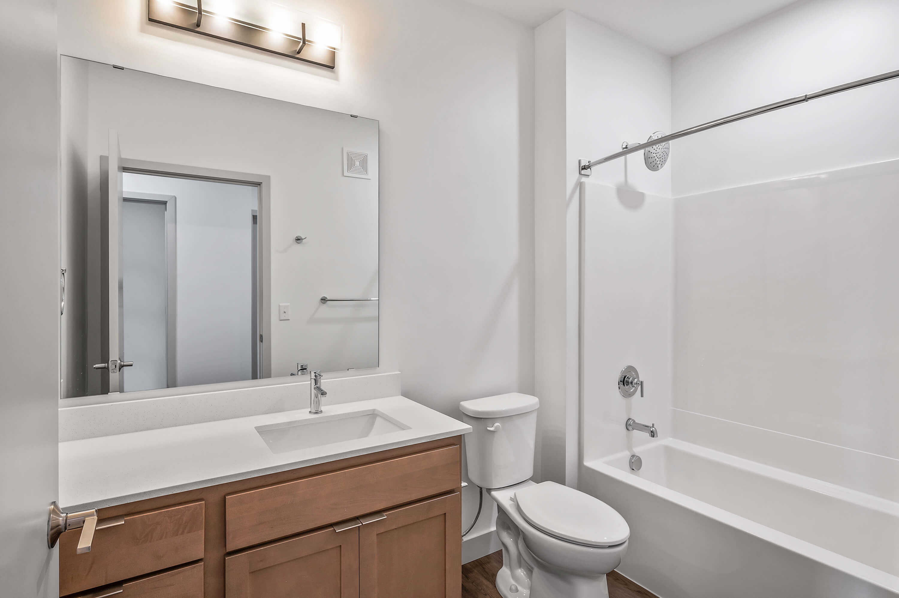 Bathroom featuring a bathtub, single sink vanity, large mirror, and modern lighting.