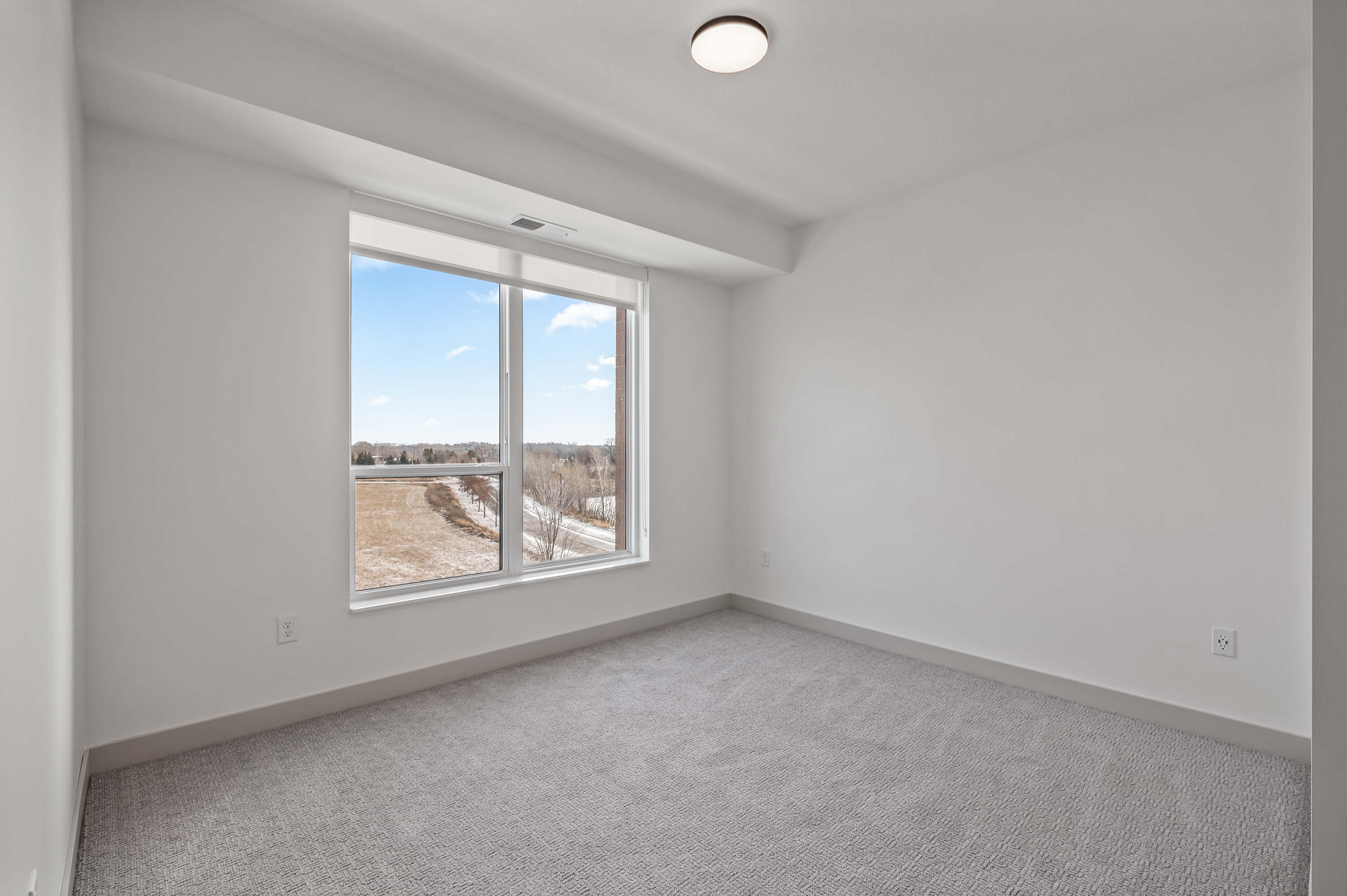 Bedroom with large window showcasing a scenic outdoor view and carpeted flooring.