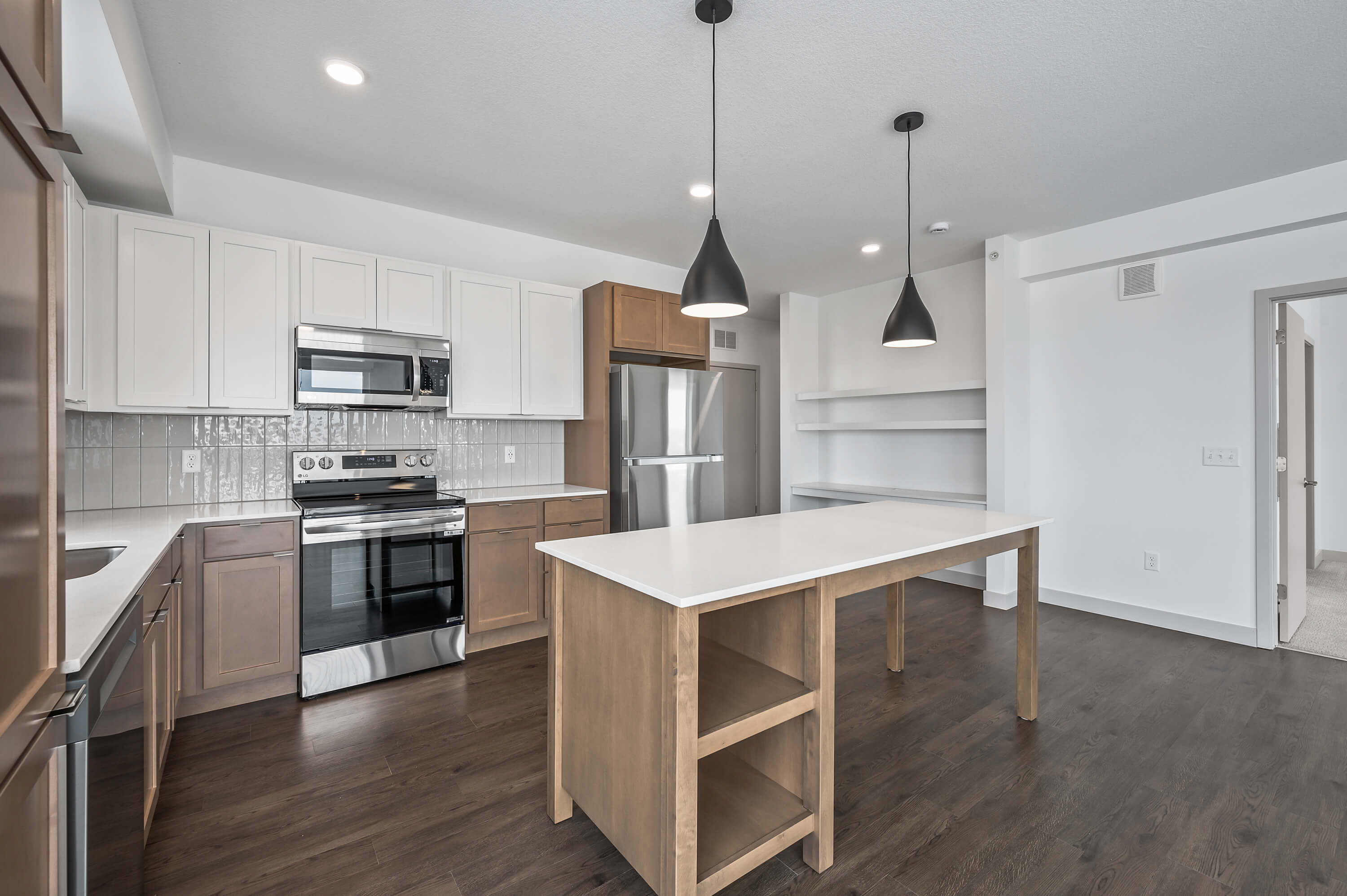 A side angle of the open-concept kitchen and living area, showcasing the natural light and wood flooring.