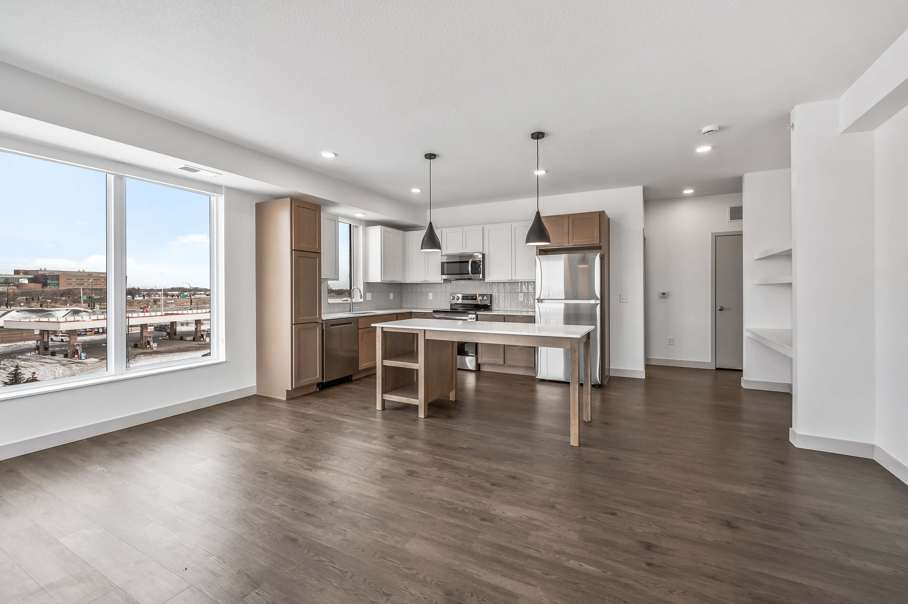 A wide view of the kitchen and living area, highlighting modern appliances, natural light, and a central island.