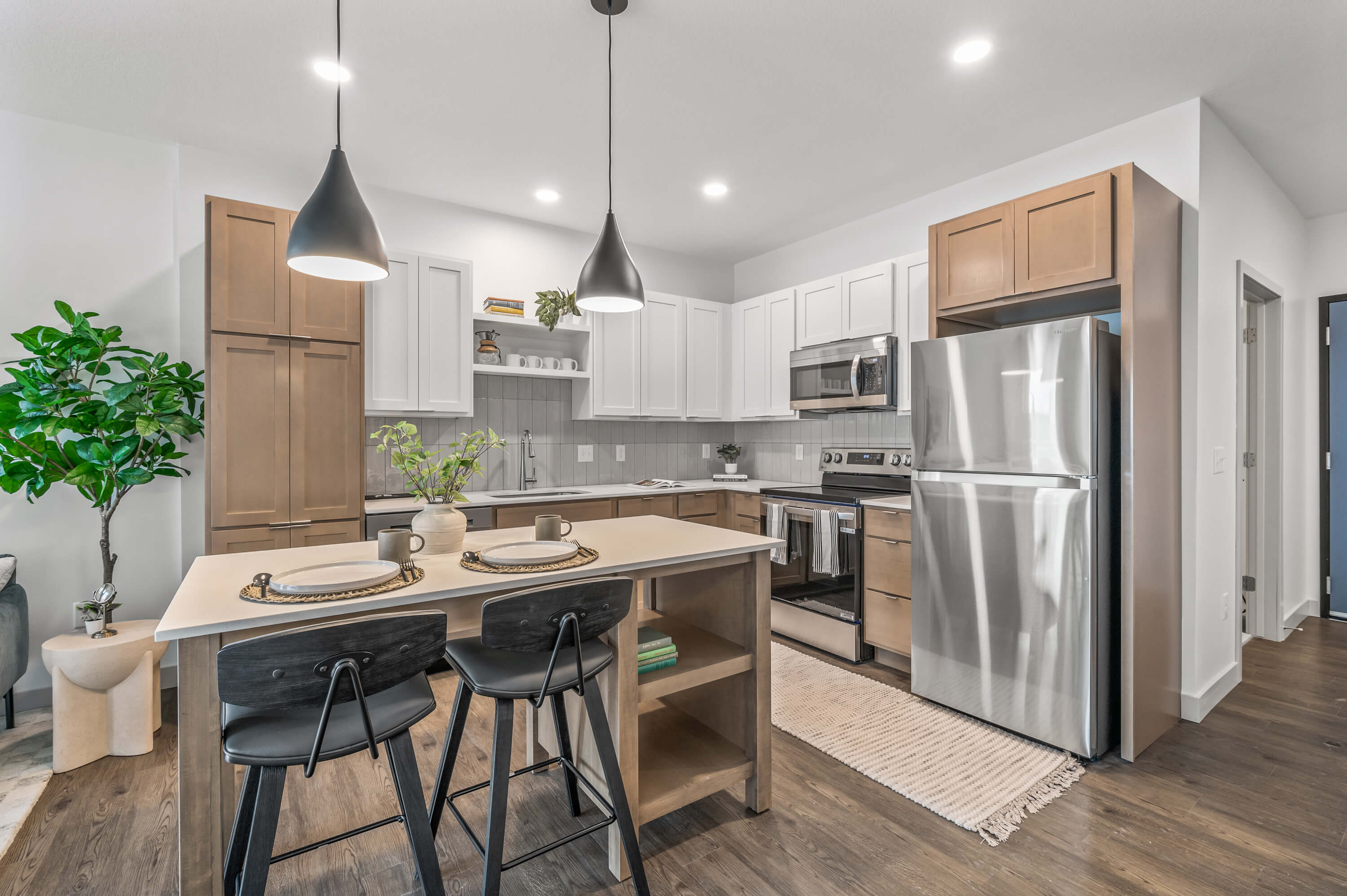 Modern kitchen featuring stainless steel appliances, pendant lighting, and a central island with seating and storage.