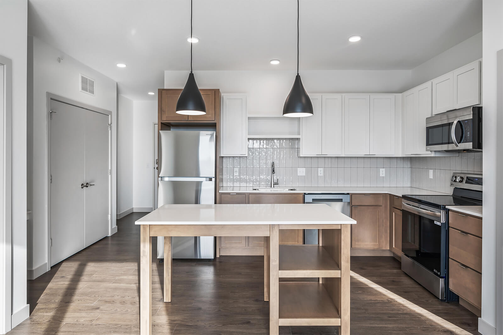 Front view of kitchen with island, pendant lighting, and stainless steel appliances