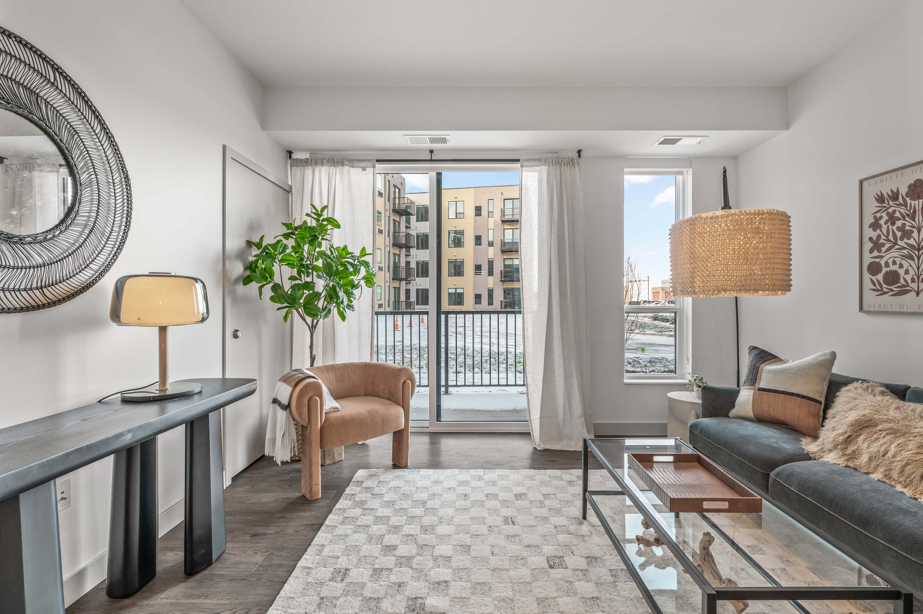 Bright living room with a view of the balcony, decorated with modern furniture and a mix of textures and greenery.