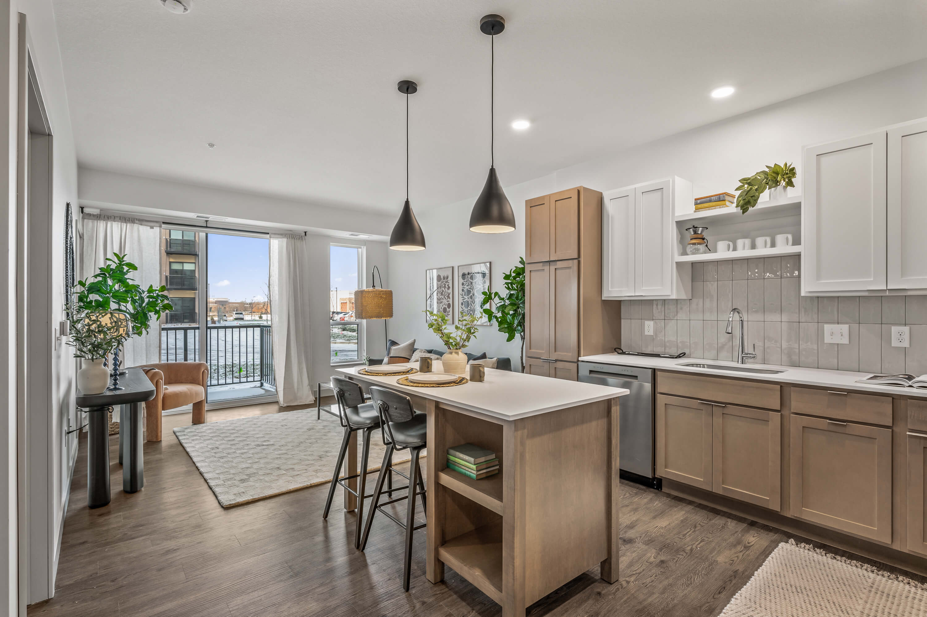 Open-concept kitchen and dining area with an island, pendant lights, and floor-to-ceiling windows leading to a balcony.