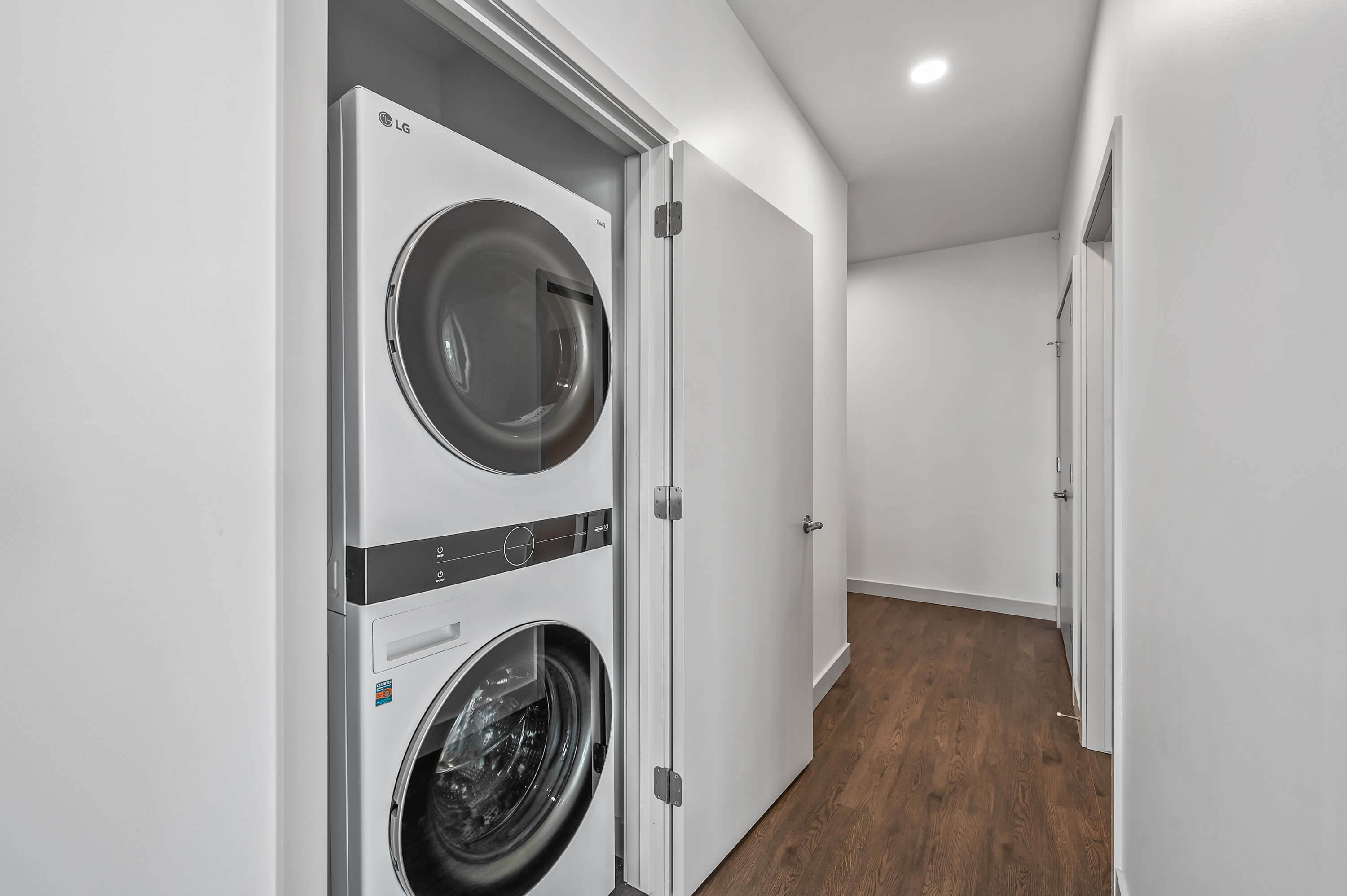 A hallway with a laundry closet, showcasing a stacked washer and dryer unit.