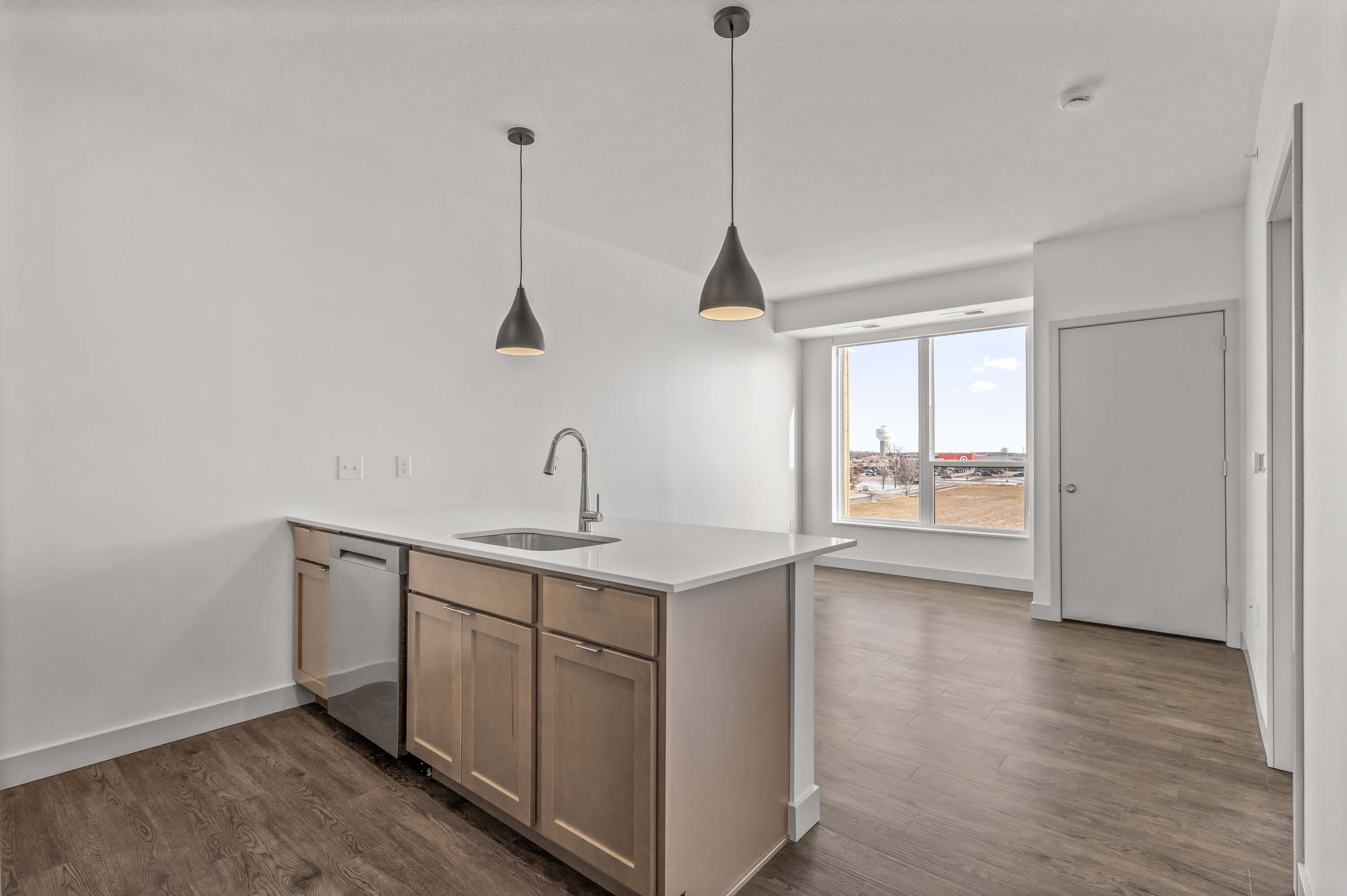 Kitchen view with island, sink, and pendant lighting, adjacent to large windows with outdoor scenery.