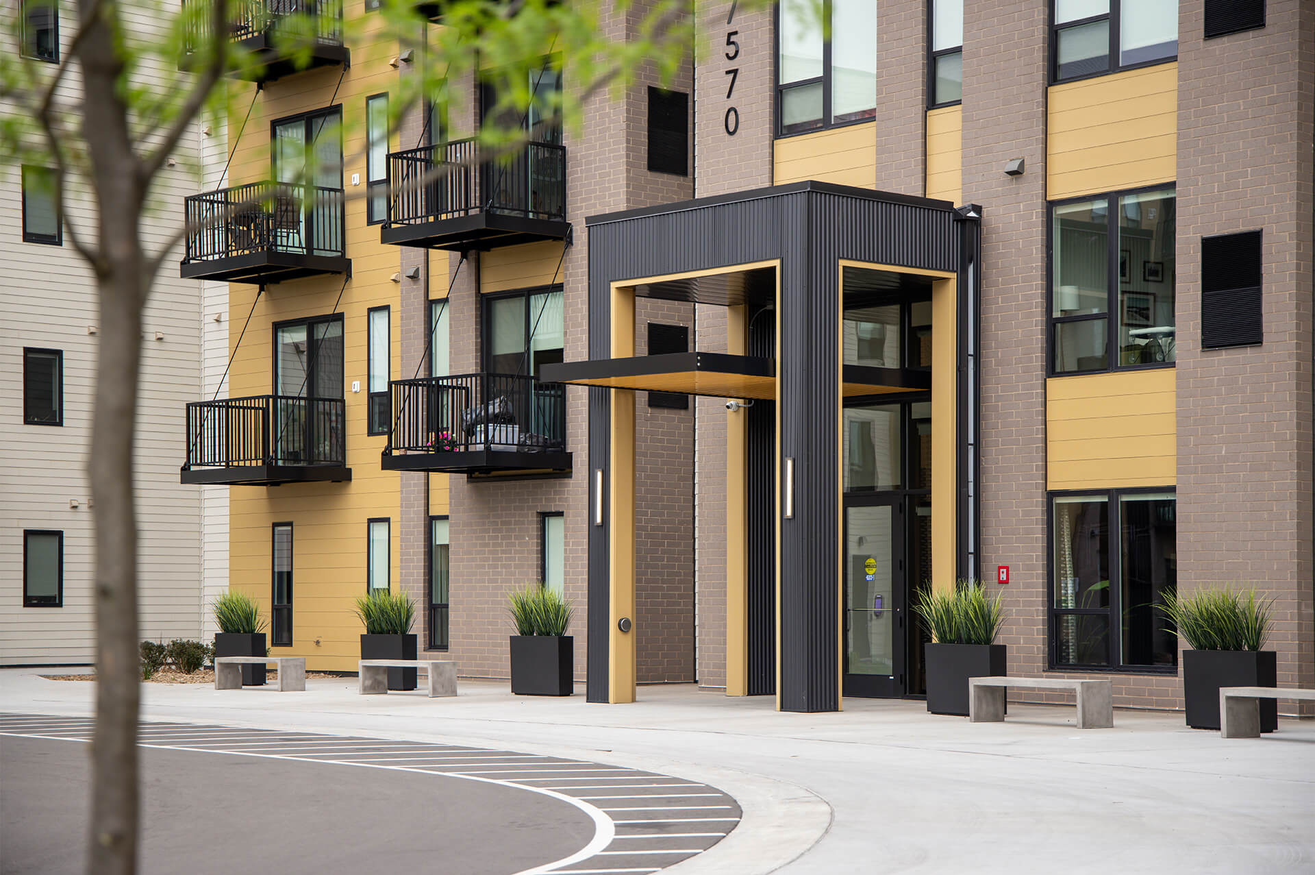 Modern front entrance of The Harlan Oakdale apartments with black and gold trim