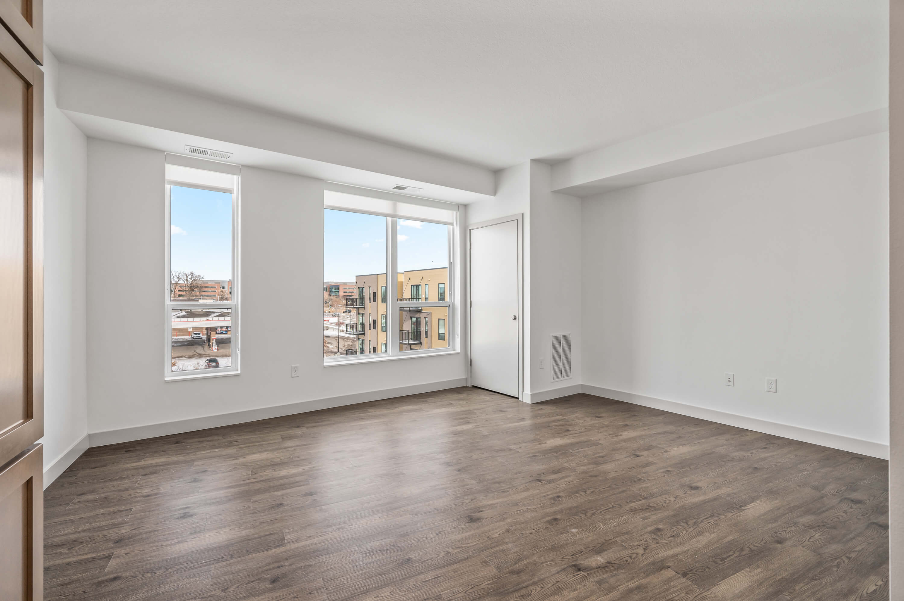 Bedroom with beige carpet, white walls, and closet with sliding doors, connected to the kitchen area.