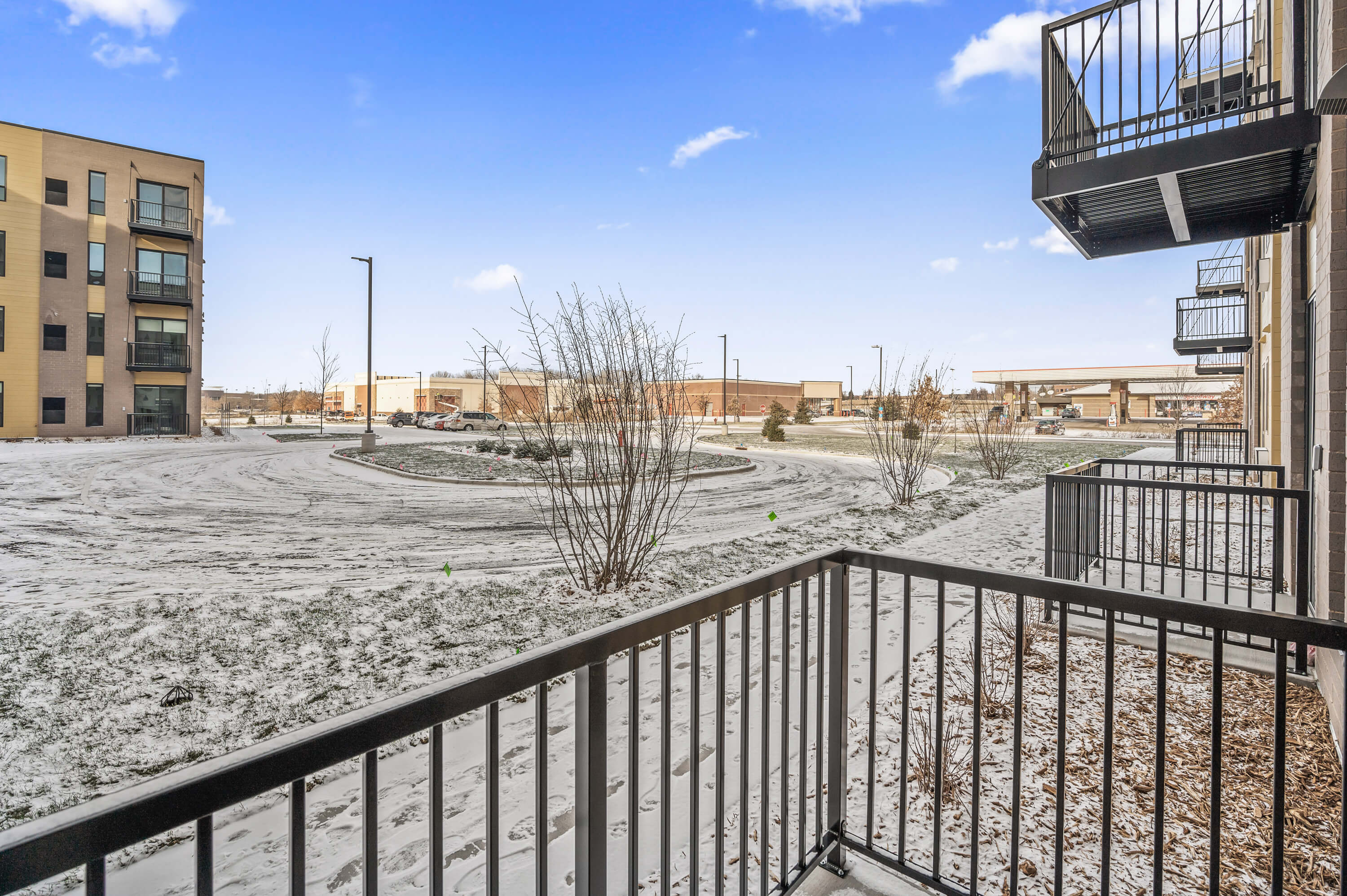 Side view from a balcony showcasing a snowy courtyard and nearby apartment buildings.