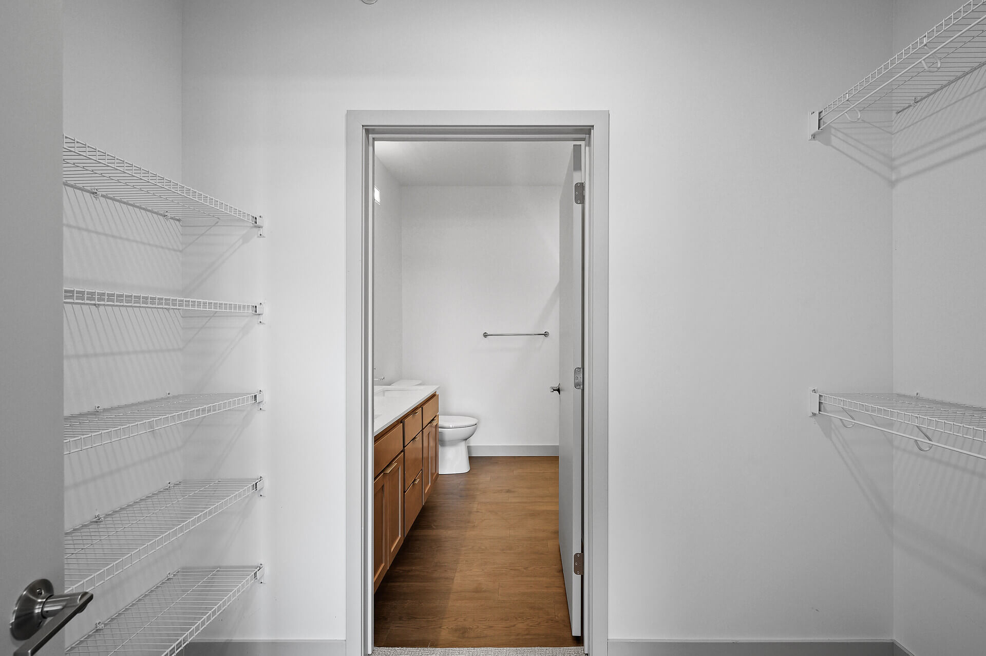 Hallway view leading to bathroom with shelves for storage on the side.