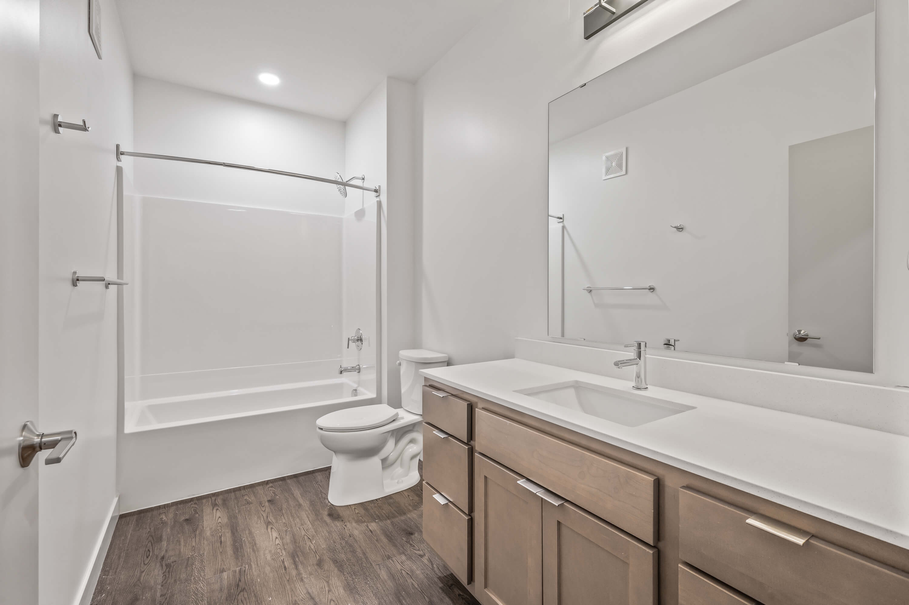 A view of the kitchen area with white and wooden cabinetry and a large open living space.