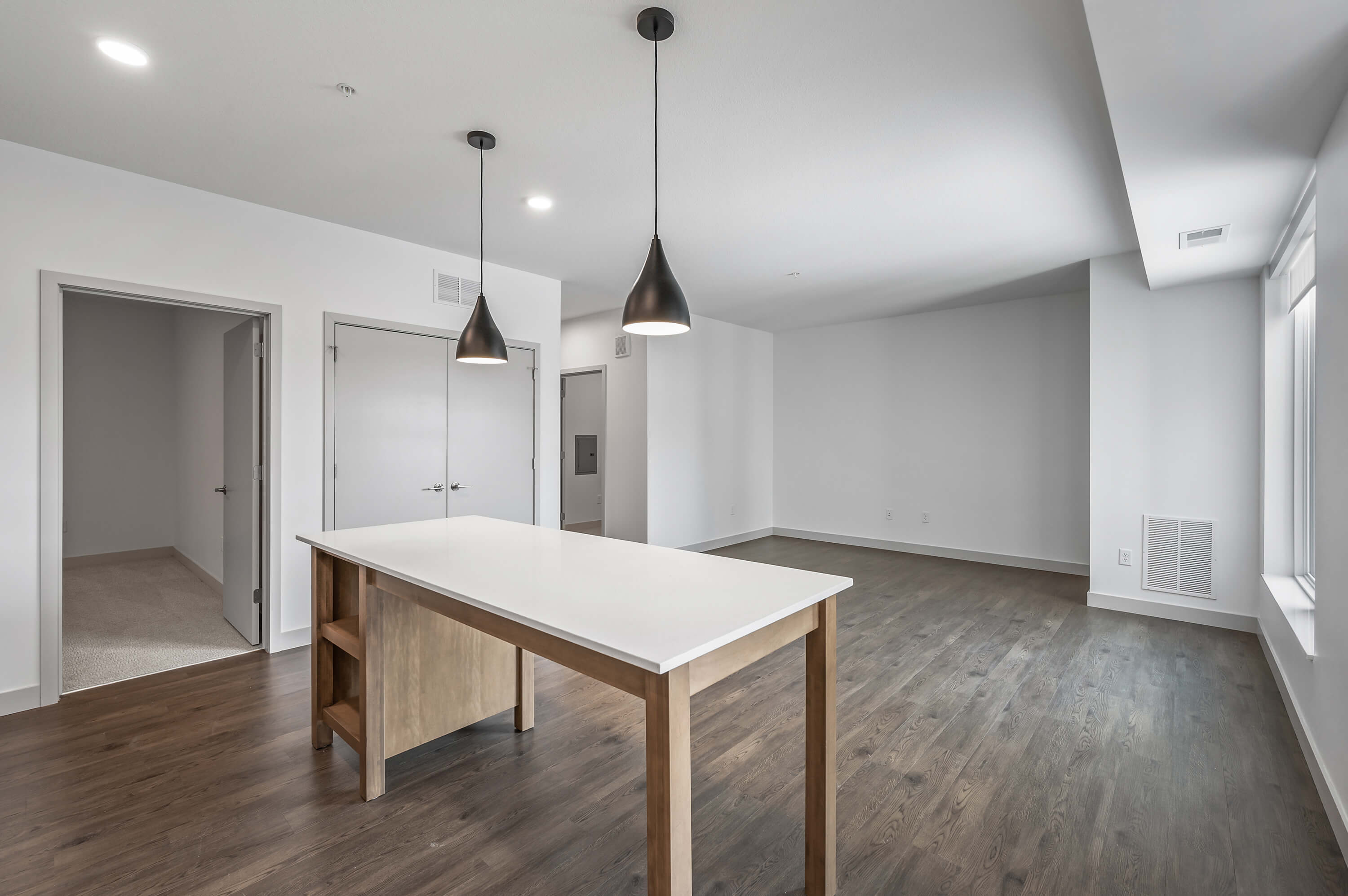 Living area with natural light pouring through large windows, adjacent to the kitchen.