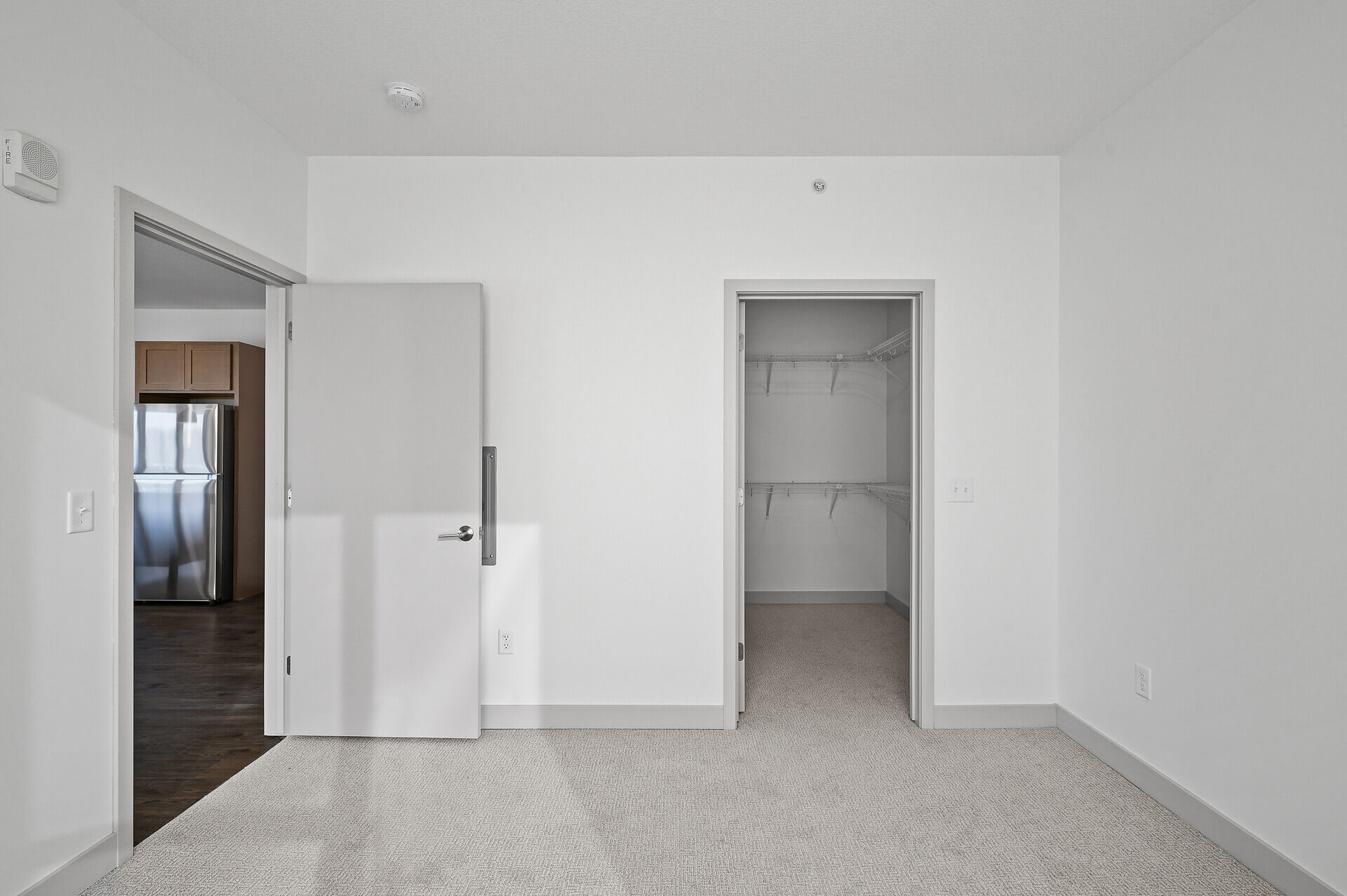 Walk-in closet with storage shelves and door leading to another room