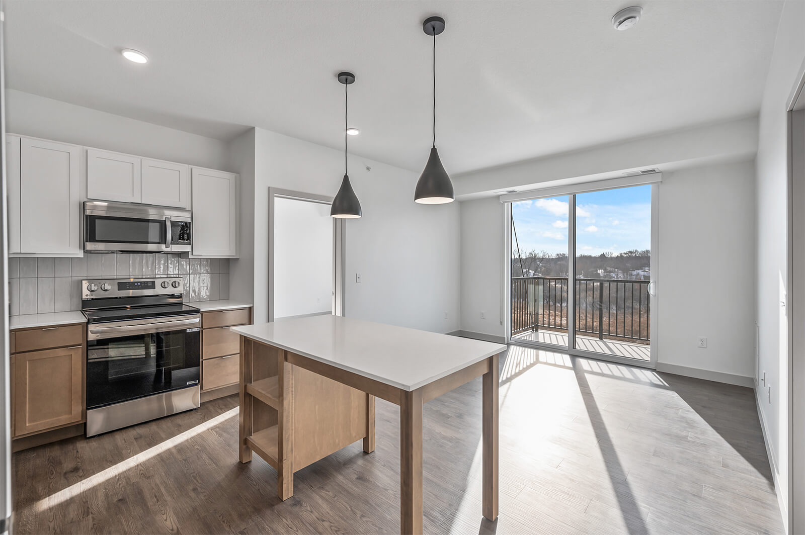 Kitchen with island and sliding glass door leading to balcony