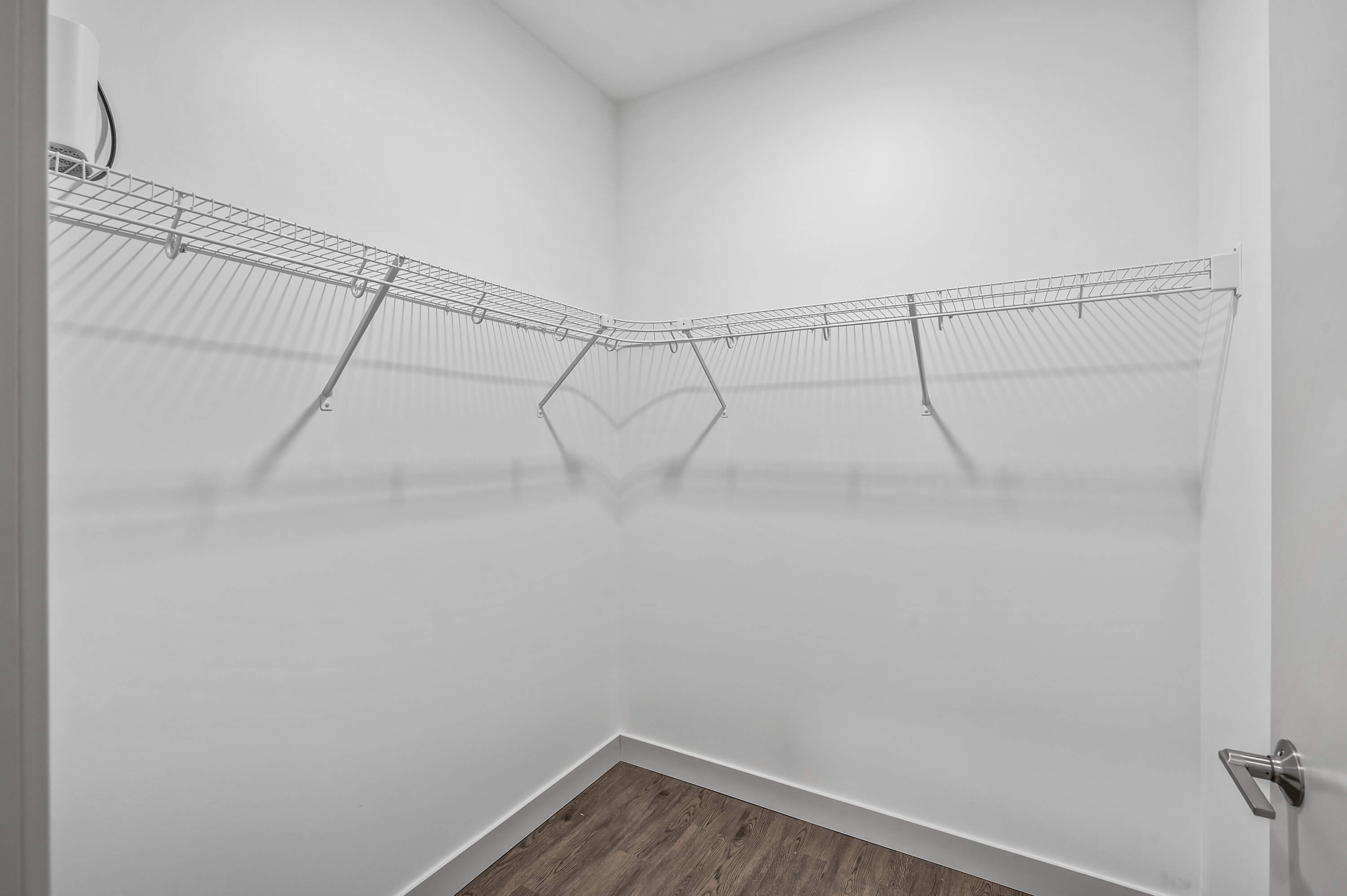 Spacious walk-in closet with white wire shelving and wood flooring.