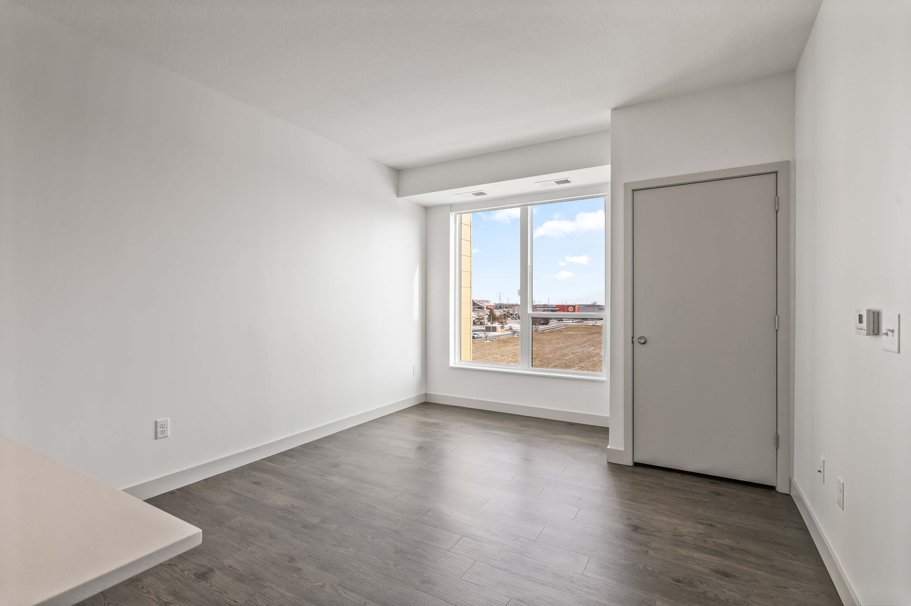 Empty living space with large windows and a door leading to another room.