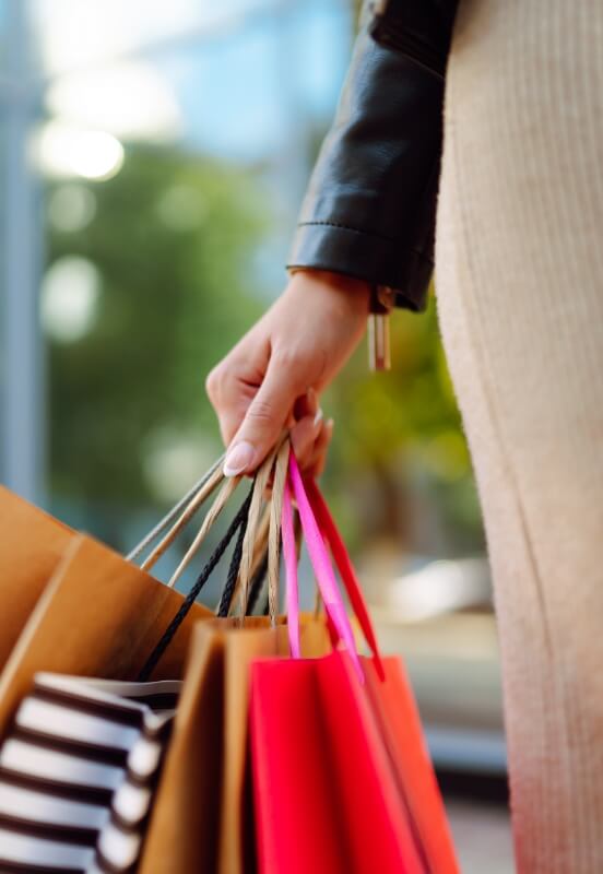 Close-up of a person's hand holding colorful shopping bags, suggesting a productive shopping session.