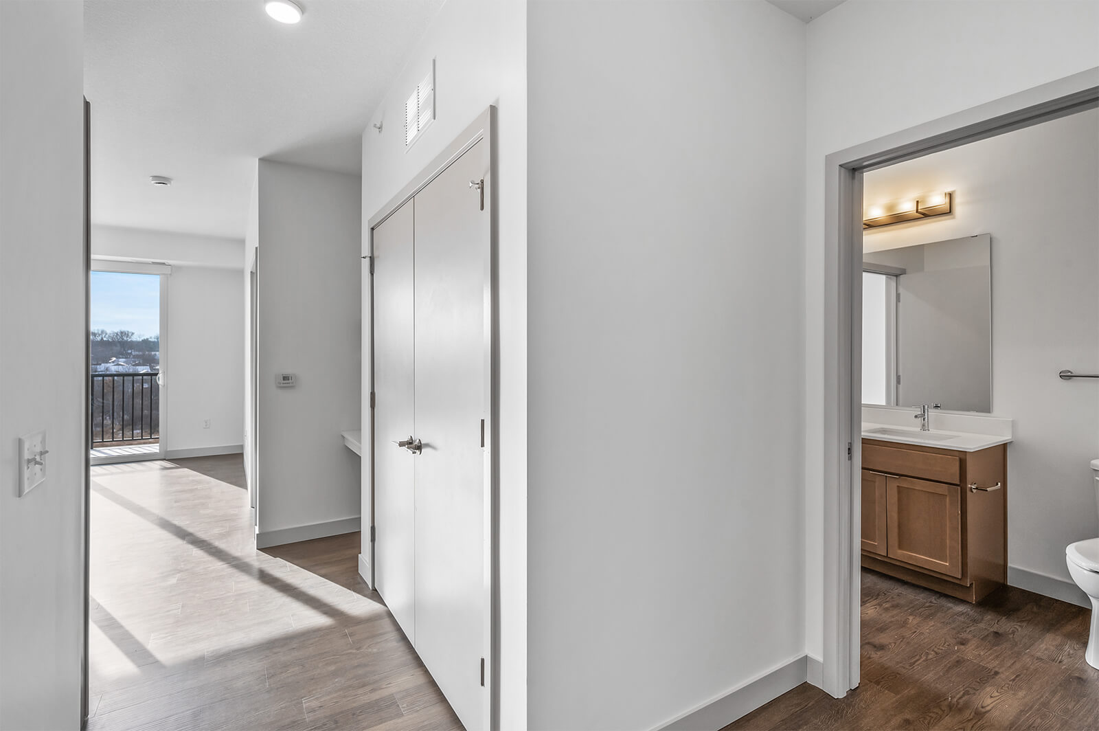 Hallway view with bathroom on right and balcony visible at the end