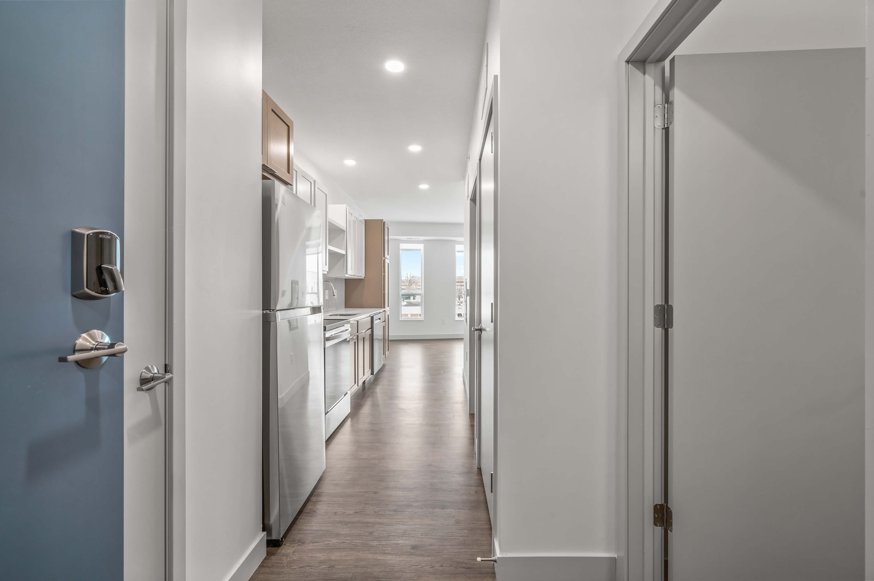 Modern kitchen with stainless steel appliances, white and wooden cabinets, and tiled backsplash.