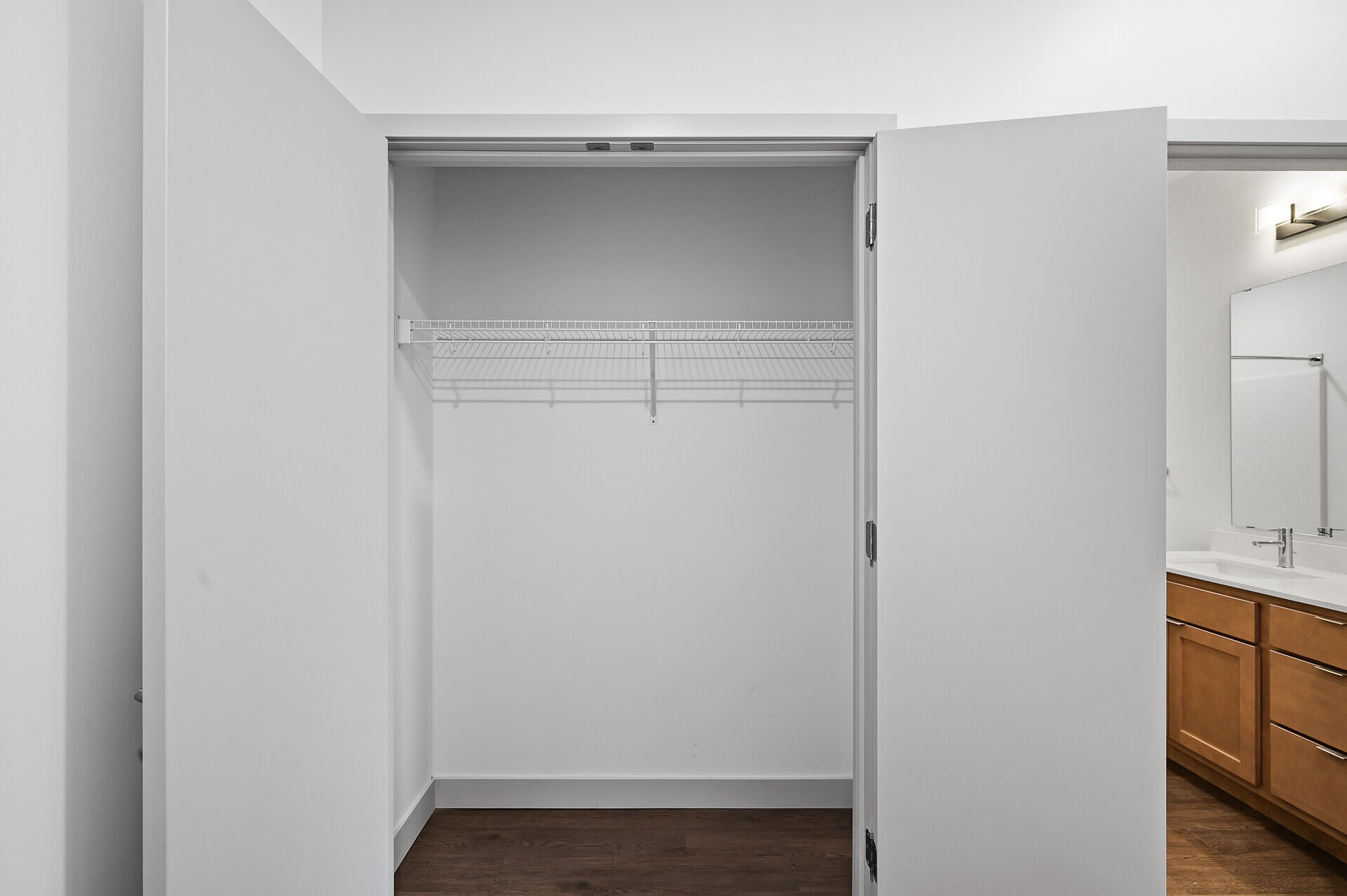 Empty closet with wire shelving and a view into the adjacent bathroom.