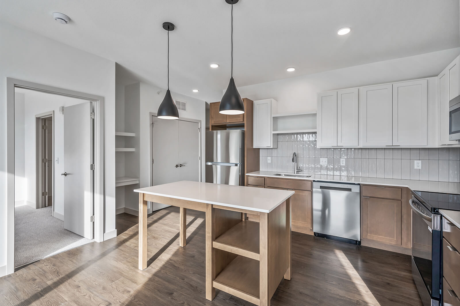Side view of kitchen with island, pendant lights, and open shelving