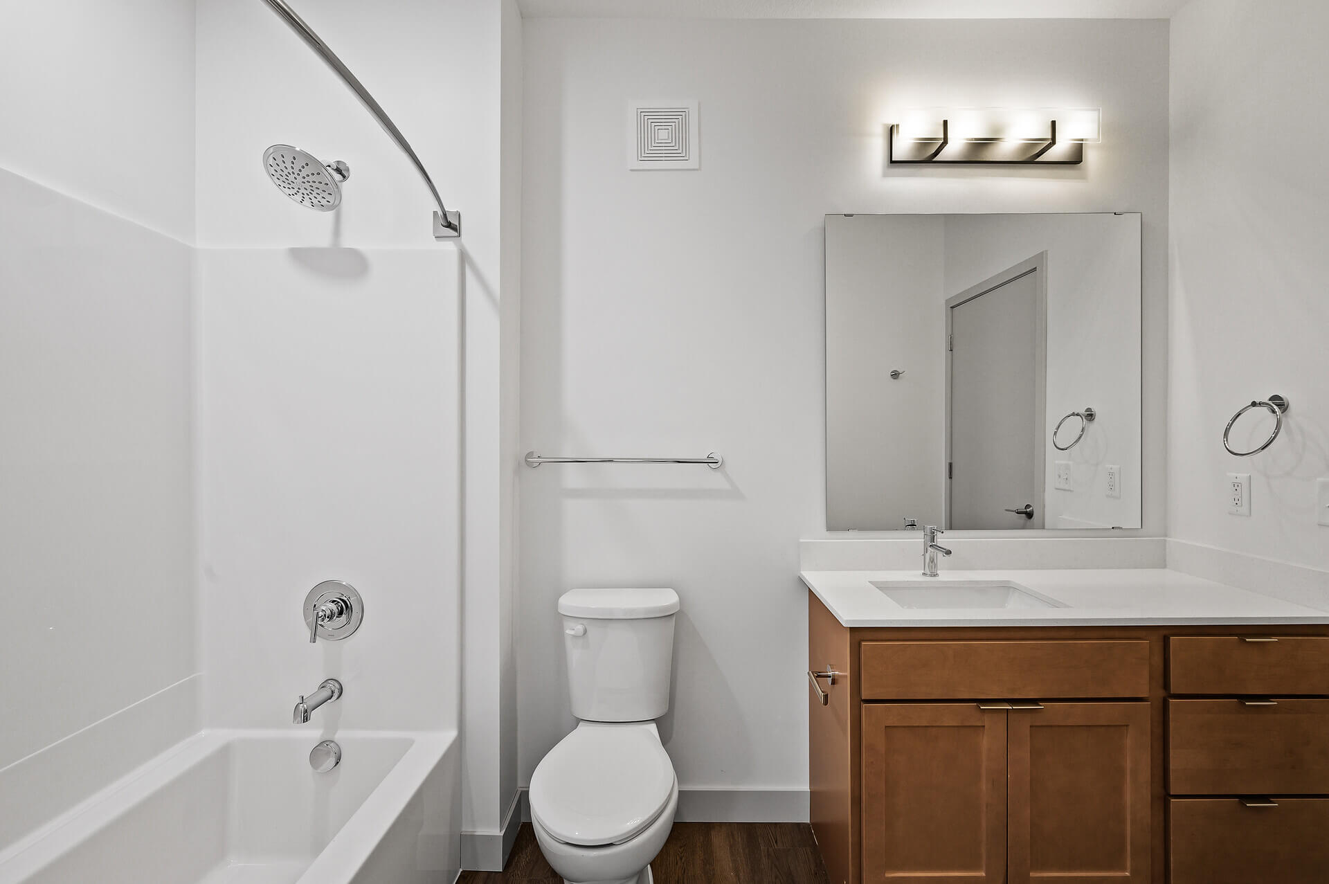 Modern bathroom with large mirror and wooden vanity.