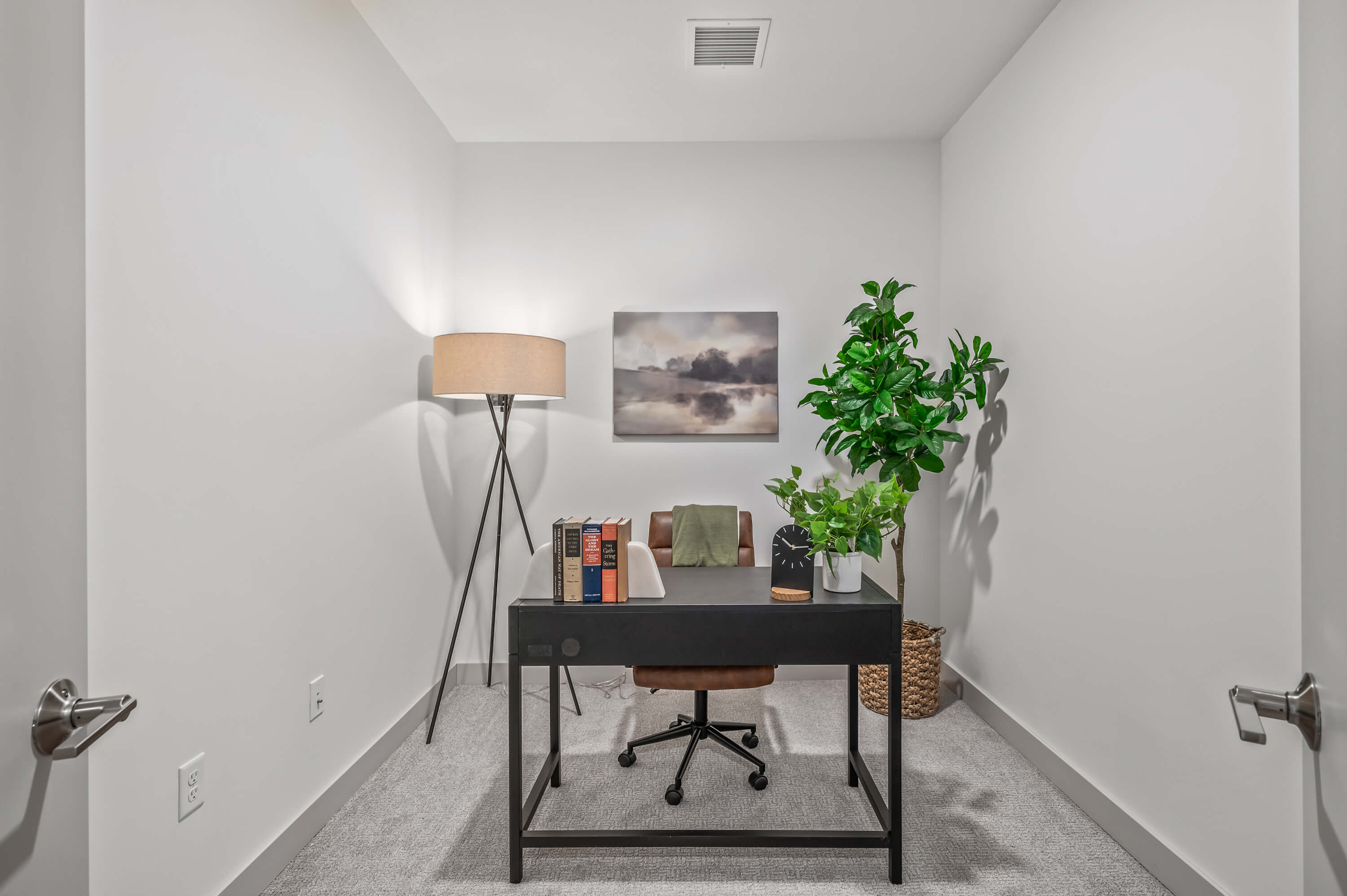 Minimalist home office with a desk, books, a modern lamp, and greenery accents.