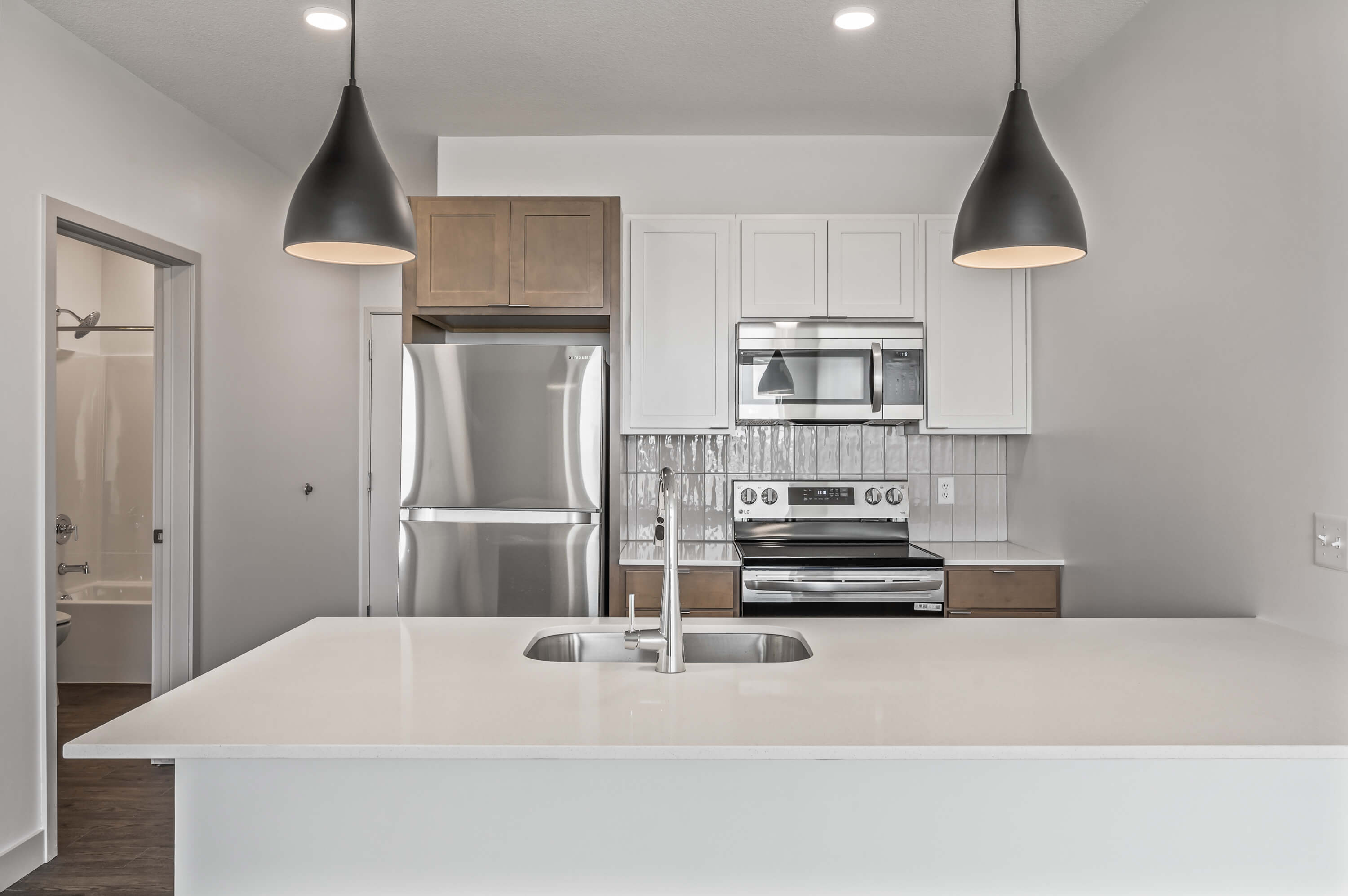 Close-up view of the refrigerator and microwave in the kitchen area with cabinets.