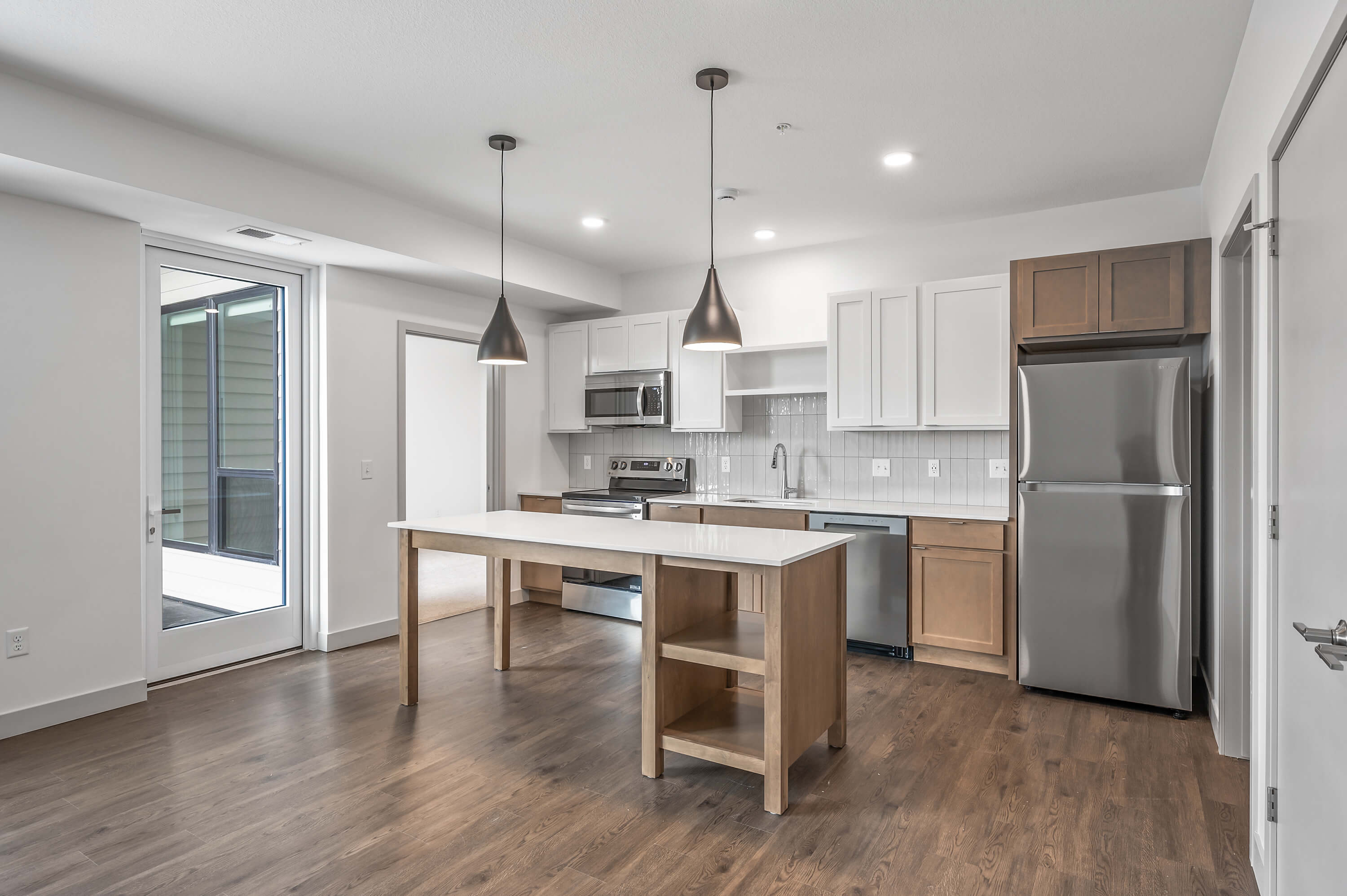 Kitchen with a large island, pendant lighting, and a door leading to a patio or balcony.