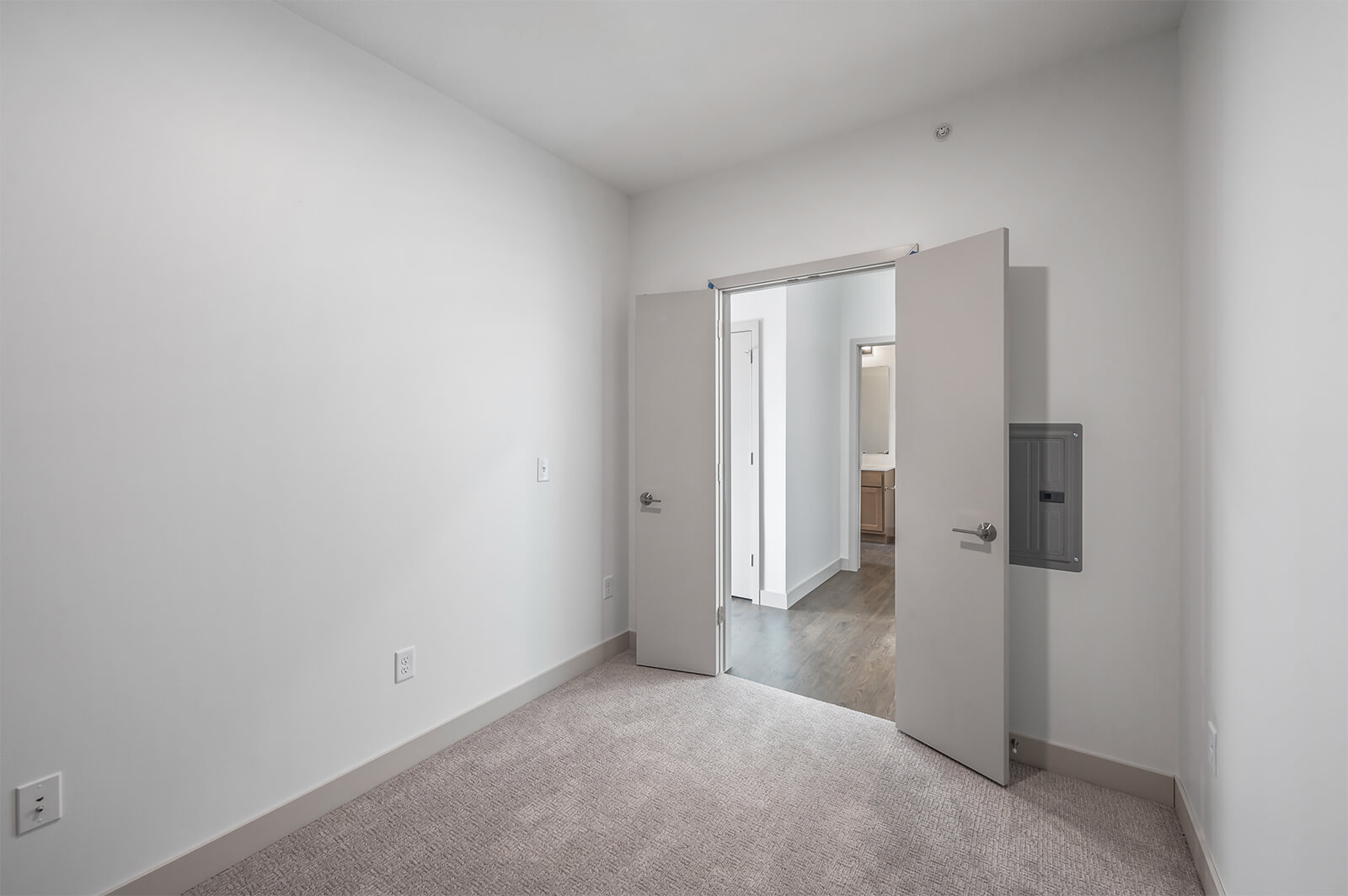 Carpeted room with double doors open to hallway
