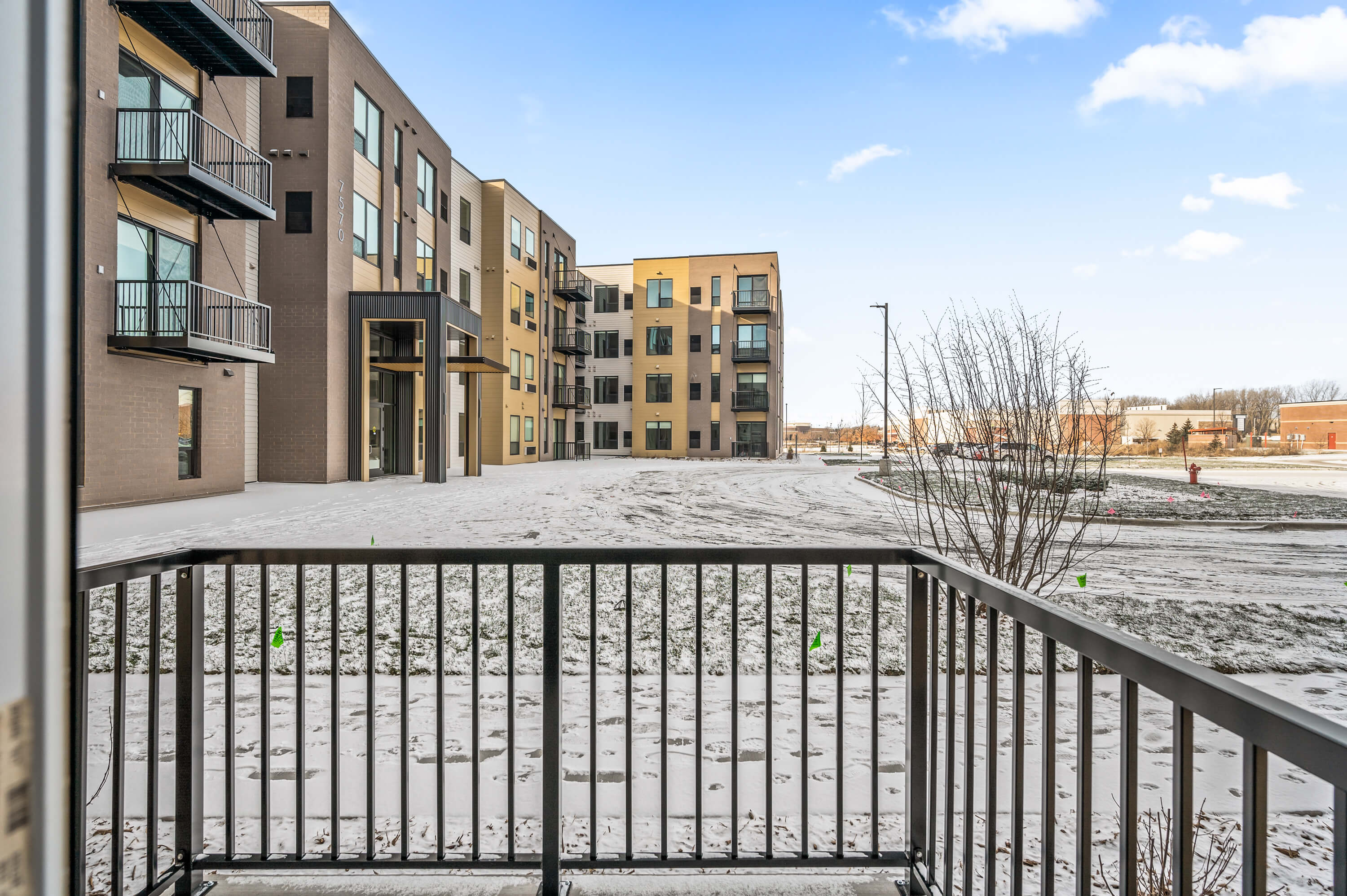 Balcony view overlooking a snowy landscape with modern apartment buildings in the distance.