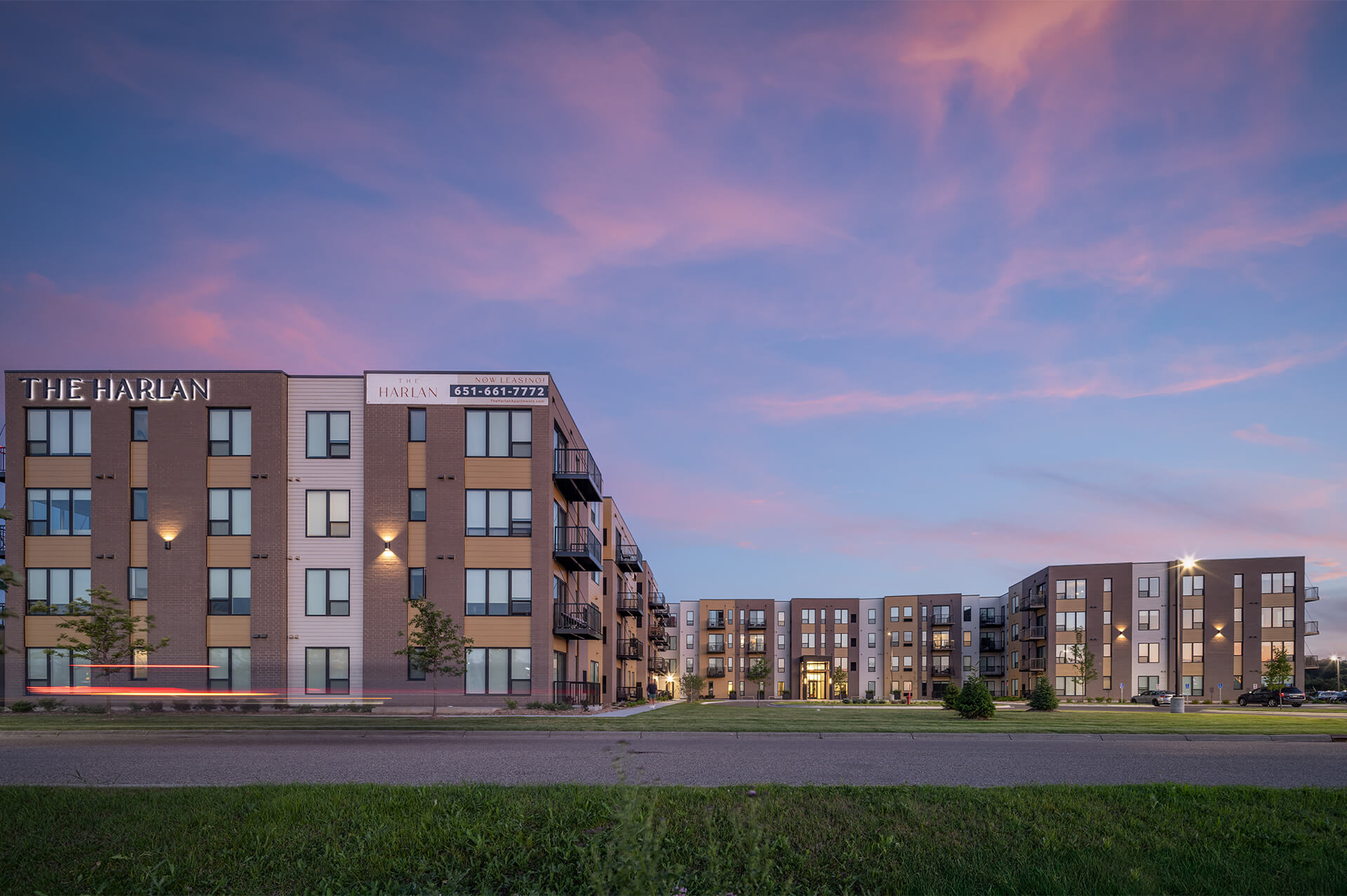 Exterior view of The Harlan Oakdale apartments at dusk with vibrant sky