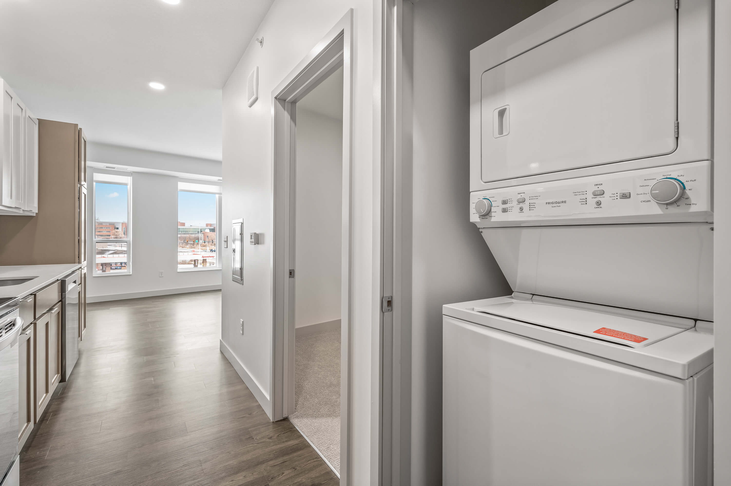 A modern kitchen with a mix of white and wooden cabinets, tiled backsplash, and stainless steel appliances.