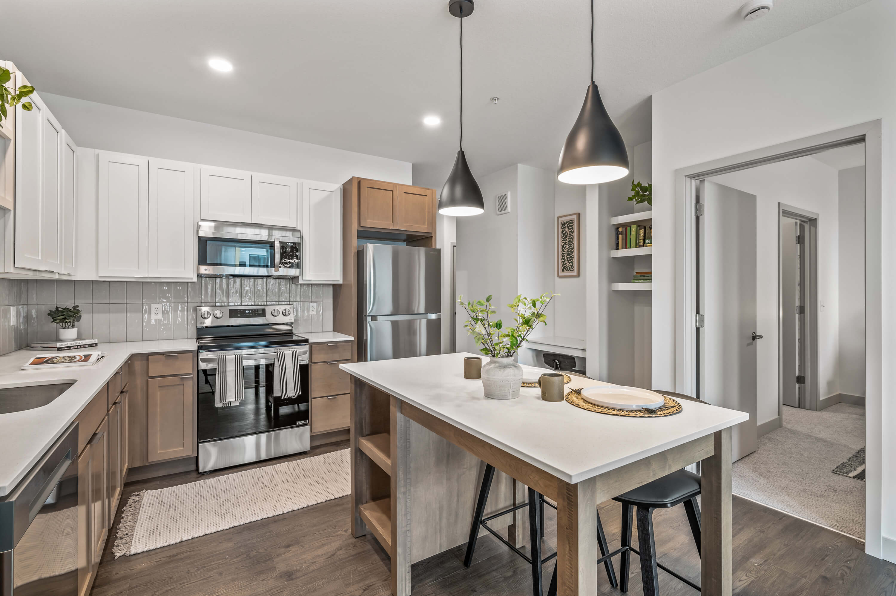 Kitchen and dining area with a modern design, featuring sleek pendant lights and open shelving with decorative items.